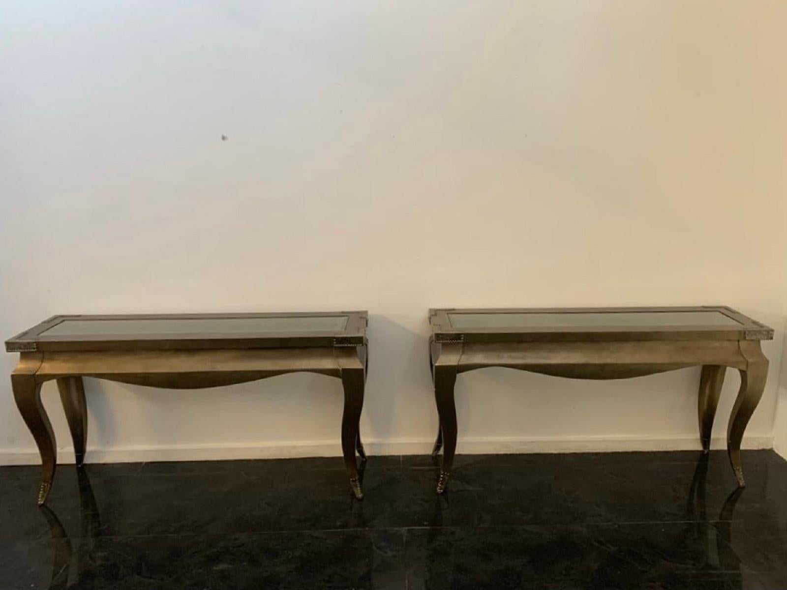 Pair of eclectic wood, glass and metal console tables, 1980s. Bronze-colored metallic finish, studded and patinated metal corners and tips.
Packaging with bubble wrap and cardboard boxes is included. If the wooden packaging is needed (fumigated