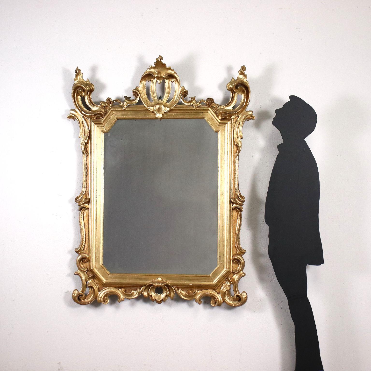 Eclectic mirror, the frame is carved with scrolls and rocaille motifs in Baroque style, entirely gilded.