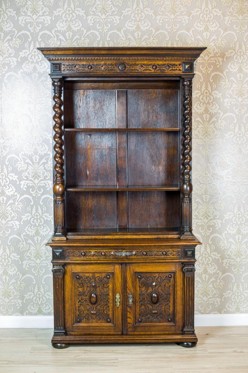 We present you this massive piece of furniture made of solid oak wood, dated the late 19th century.
The cupboard is composed of a double-leaf base with a drawer and an open upper section with the shelves, which is topped with a cornice.
The leaves