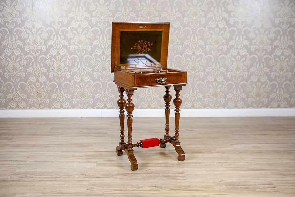 Eclectic Walnut Wood and Veneer Sewing Table, Circa 1900

We present you this sewing table that has been made in walnut wood.
The piece of furniture is in a rectangular form on two turned, baluster supports which are joint together with a cross bar