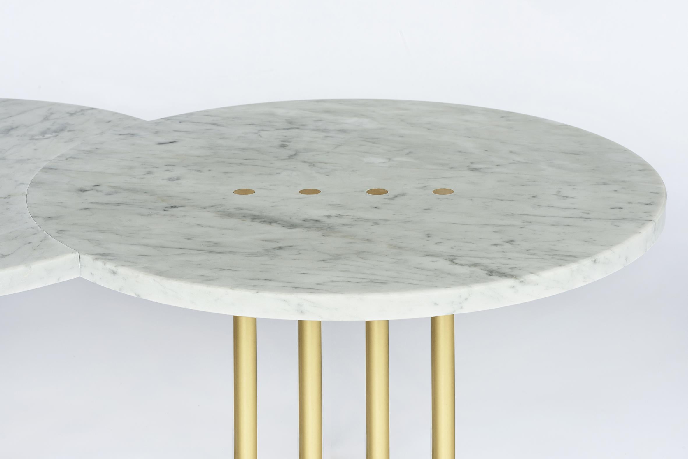 Two tables joined to form one, as when an eclipse universally unites two planets, struck by the excruciating light of the sun that forms small brushed brass dots.

The sun's rays support the table's structure.
For a contemporary, minimal and