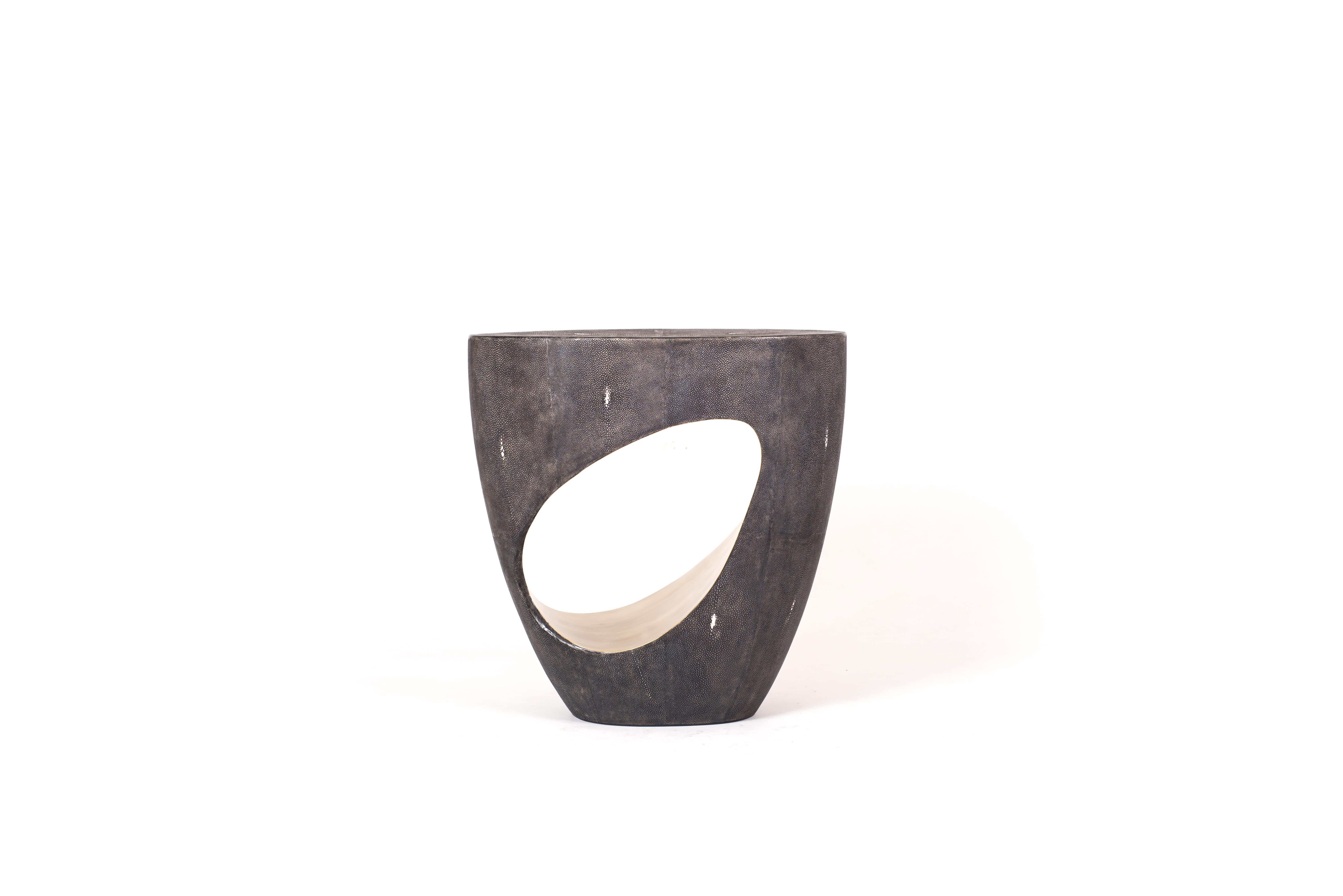 The Eclipse stool in coal black shagreen by R&Y Augousti is geometric and sculptural. A jewel-like amorphous shape, this piece is completely inlaid in shagreen, while the cut cutout opening is inlaid inside with bronze-patina brass, creating a