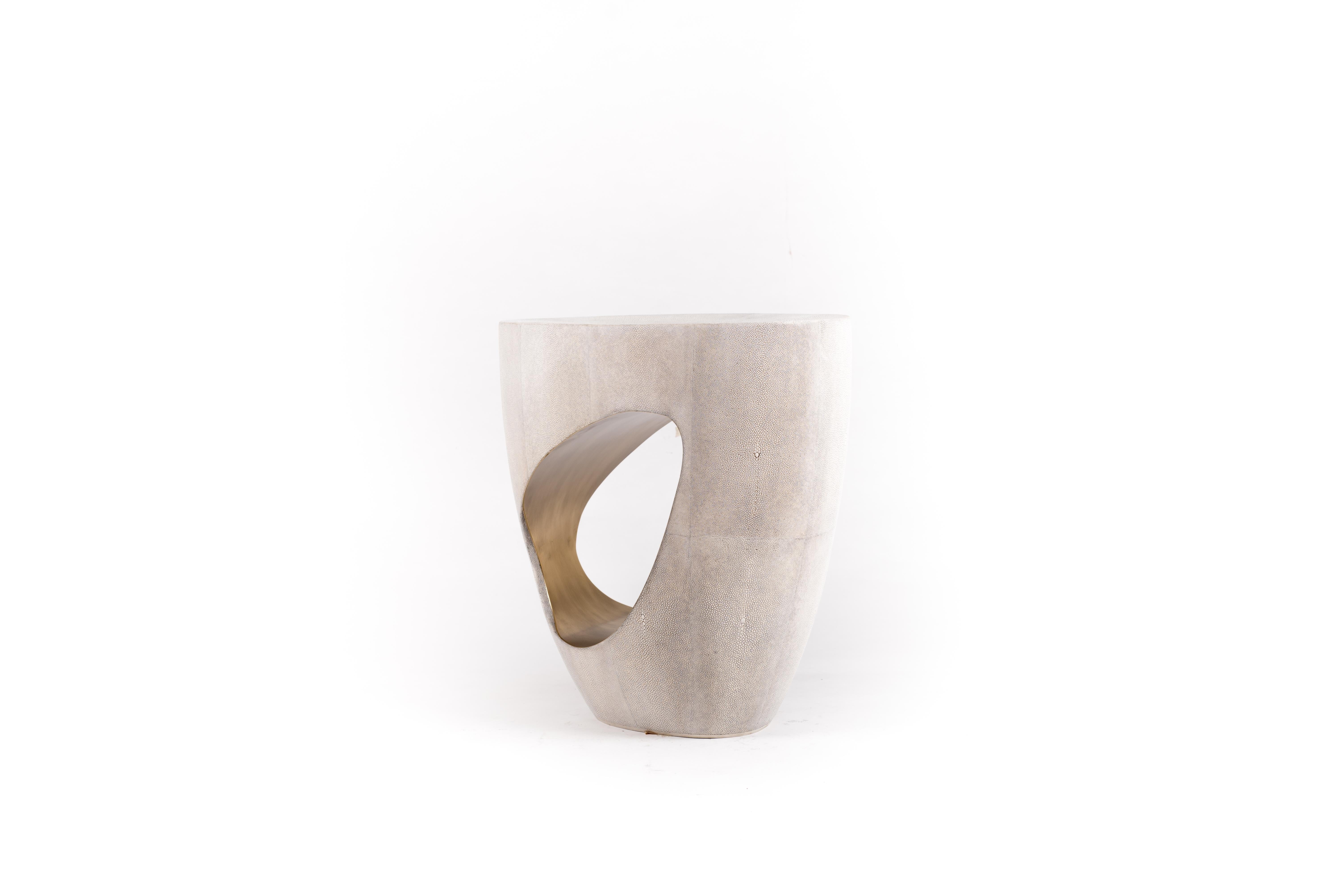 The Eclipse stool in cream shagreen by R&Y Augousti is geometric and sculptural. A jewel-like amorphous shape, this piece is completely inlaid in shagreen, while the cut cutout opening is inlaid inside with bronze-patina brass, creating a subtle and