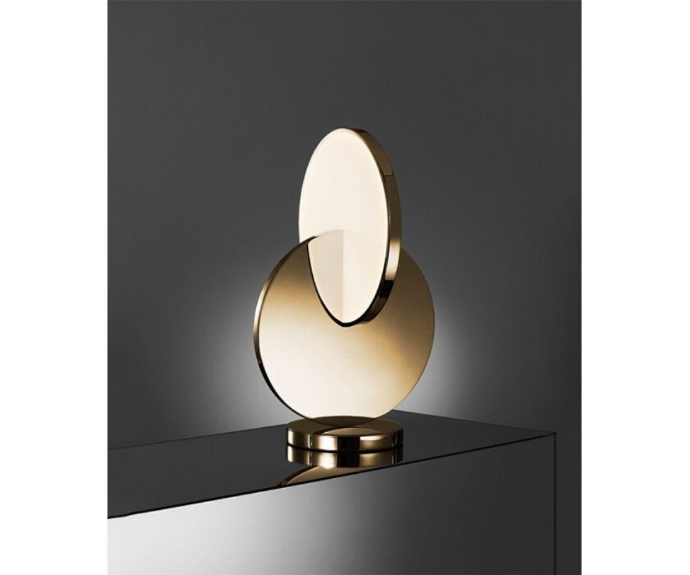 Eclipse table lamp has a sculptural silhouette with a mobile-like quality that changes at every angle. Gold and acrylic discs supported by a mirror-polished base rotate by ninety degrees to angle the diffusion of light and reveal multiple