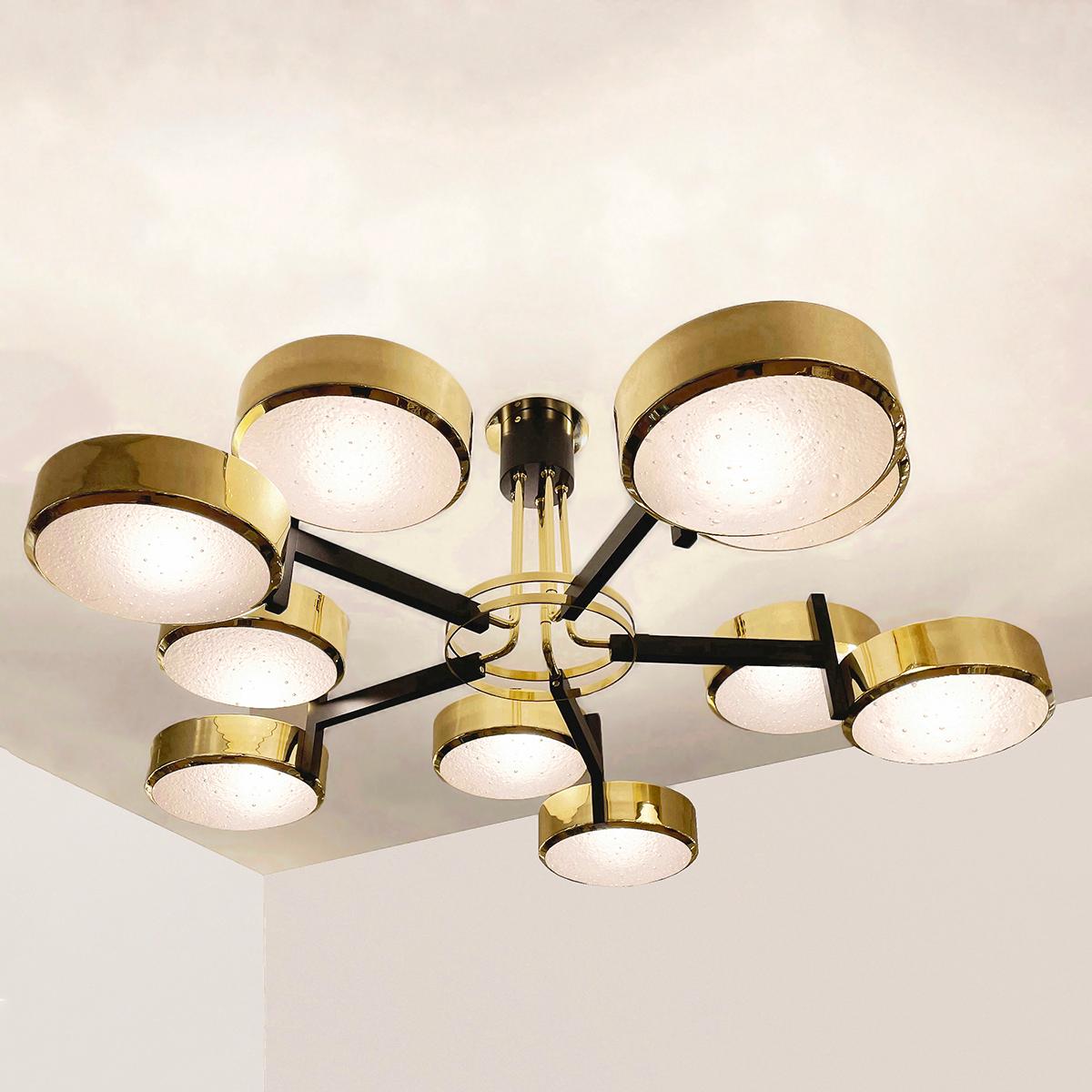 The Eclissi Grande ceiling light is designed around five pairs of eclipsing shades bound by a series of brass rings and a distinctive set of five stems. Shown in polished brass with black accents and fitted with our Murano Bubble