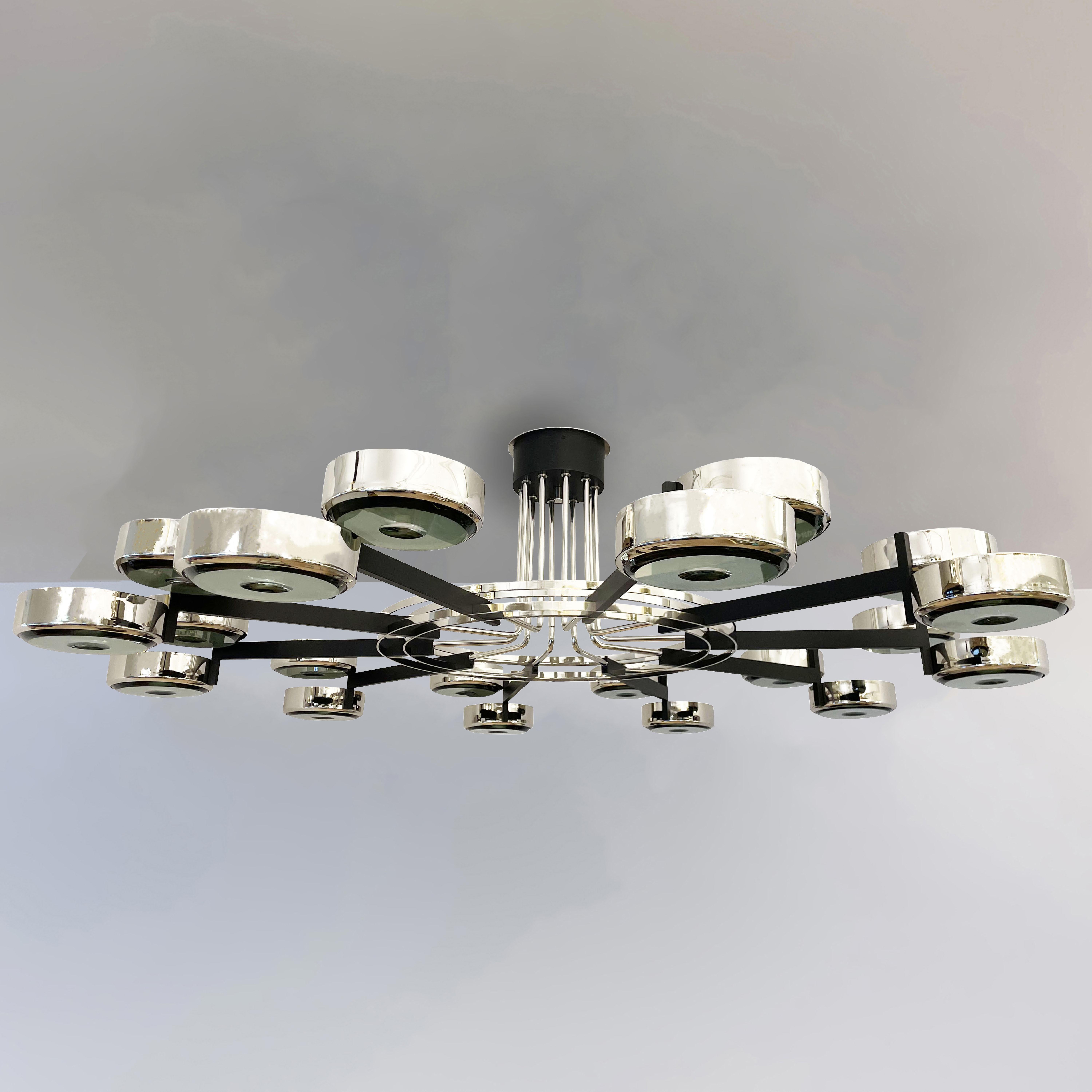The Eclissi N.20 ceiling light is the largest member of the Eclissi family spanning a colossal 70” in diameter. The piece is designed around ten pairs of eclipsing shades bound by a series of brass rings and a distinctive set of stems. Shown in