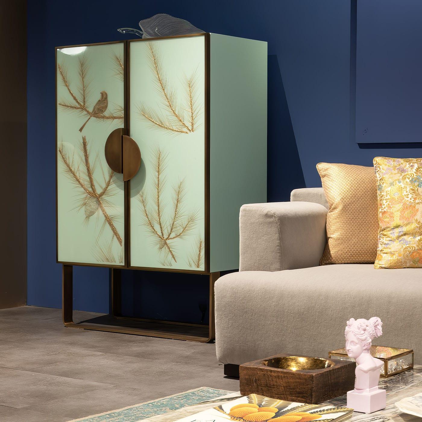 An authentic work of art, this limited-edition bar cabinet amazes with its evocative design. A sleigh base - that shares with the handles the same elegant bronzed finish - guides the eye to the doors' raised decoration of a bird perched on twigs