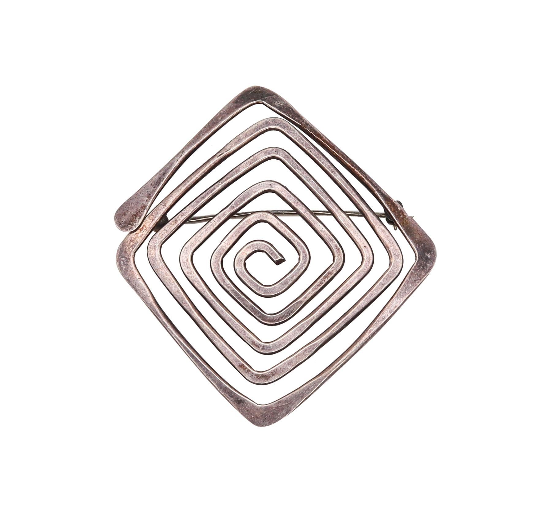 Brooch designed by Ed Wiener (1918-1991).

A modernist sculptural piece, created at the atelier of Ed Wiener in New York city, back in the 1960. This geometric brooch is composed by a simple hammered wire creating an infinite maze, with a hinged pin
