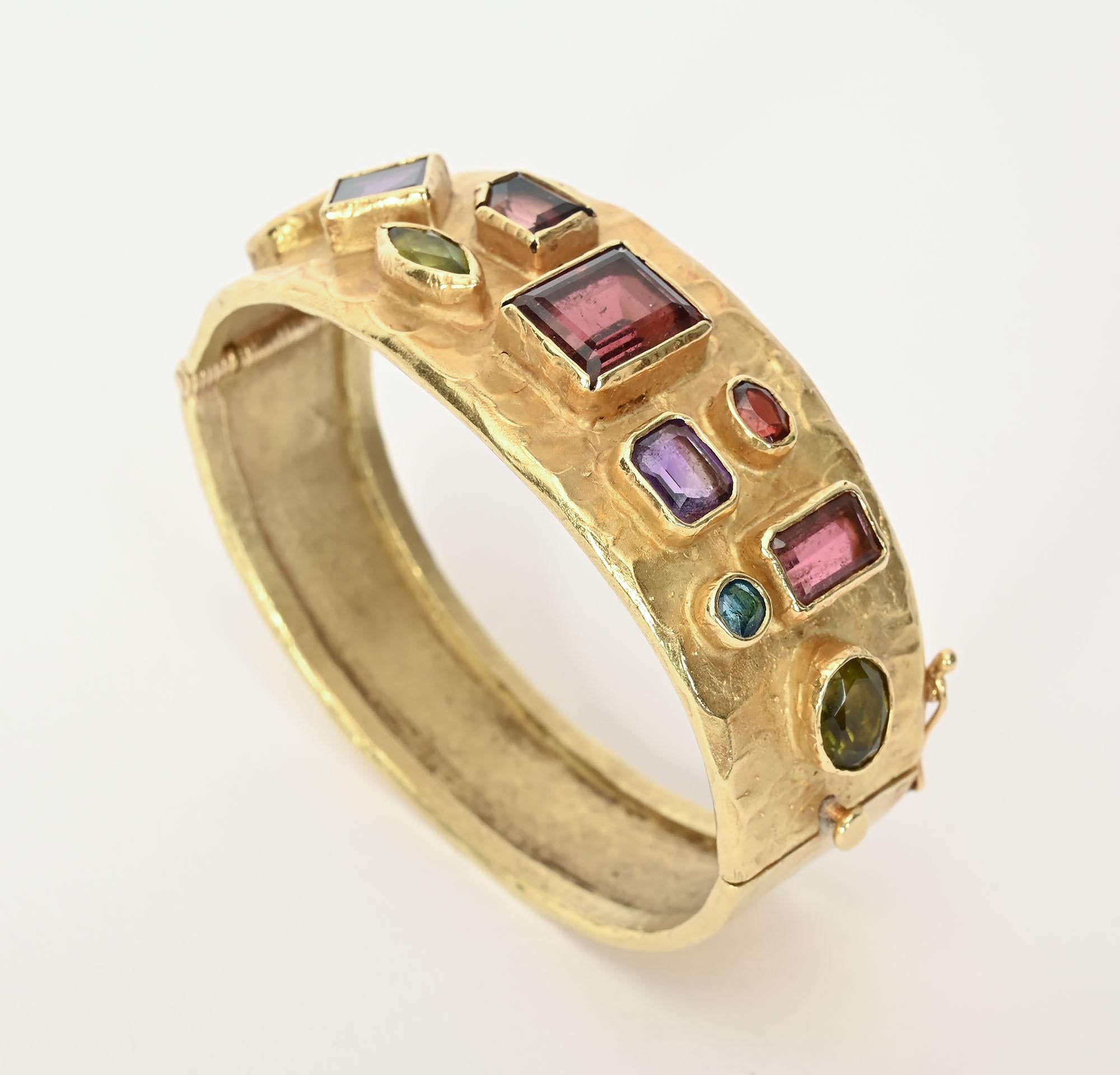 This multigem hinged bangle bracelet was made by Ed Wiener, one of the leaders of the mid-20th century Modernist jewelry movement. Wiener most often worked in silver. This heavy 18 karat gold piece was probably a  custom made piece.
 The front is