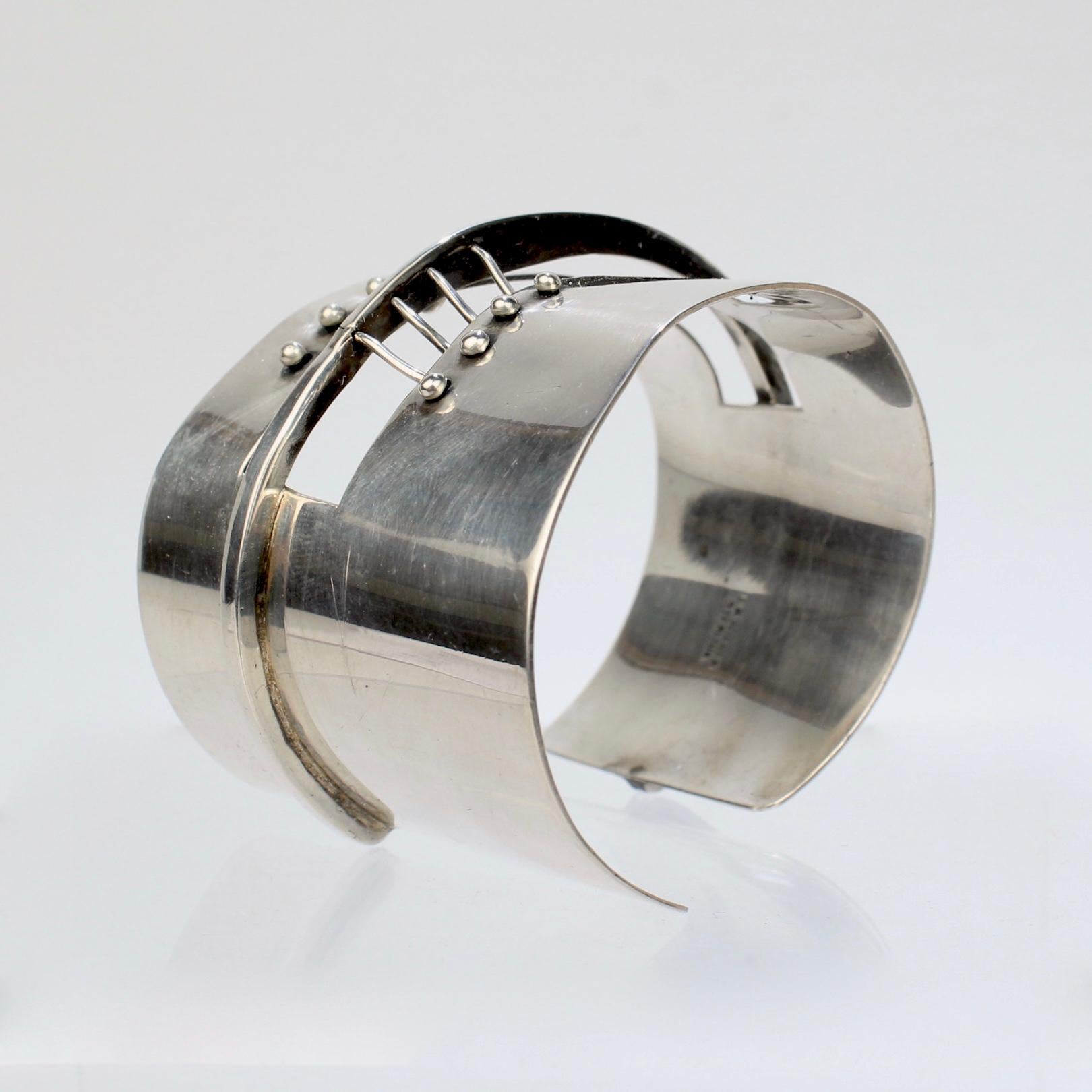 A fantastic cuff bracelet by Ed Wiener.

In sterling silver with openwork to the center and a taper to one side.

Marked: Ed Wiener and Sterling

High level design from one of the top American Modernists!

Interior Width: ca. 140 mm or 5 1/2
