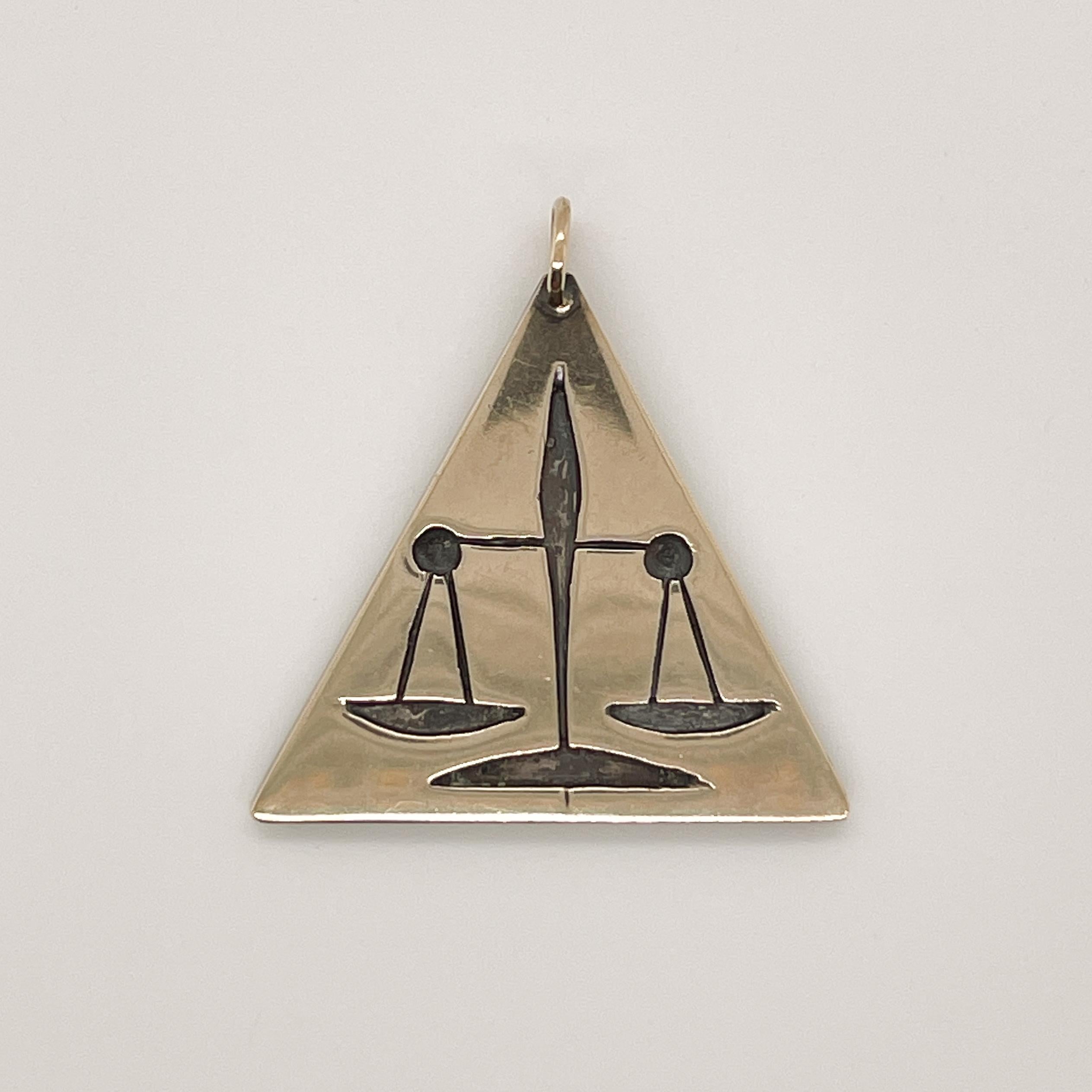 A fine pendant by Ed Wiener.

In a triangular shape.

Embossed with an equal-arm balance -- perhaps representing the Scales of Justice.

Great design from the renowned New York modernist jewelry maker!

Date:
Mid-20th Century

Overall Condition:
It