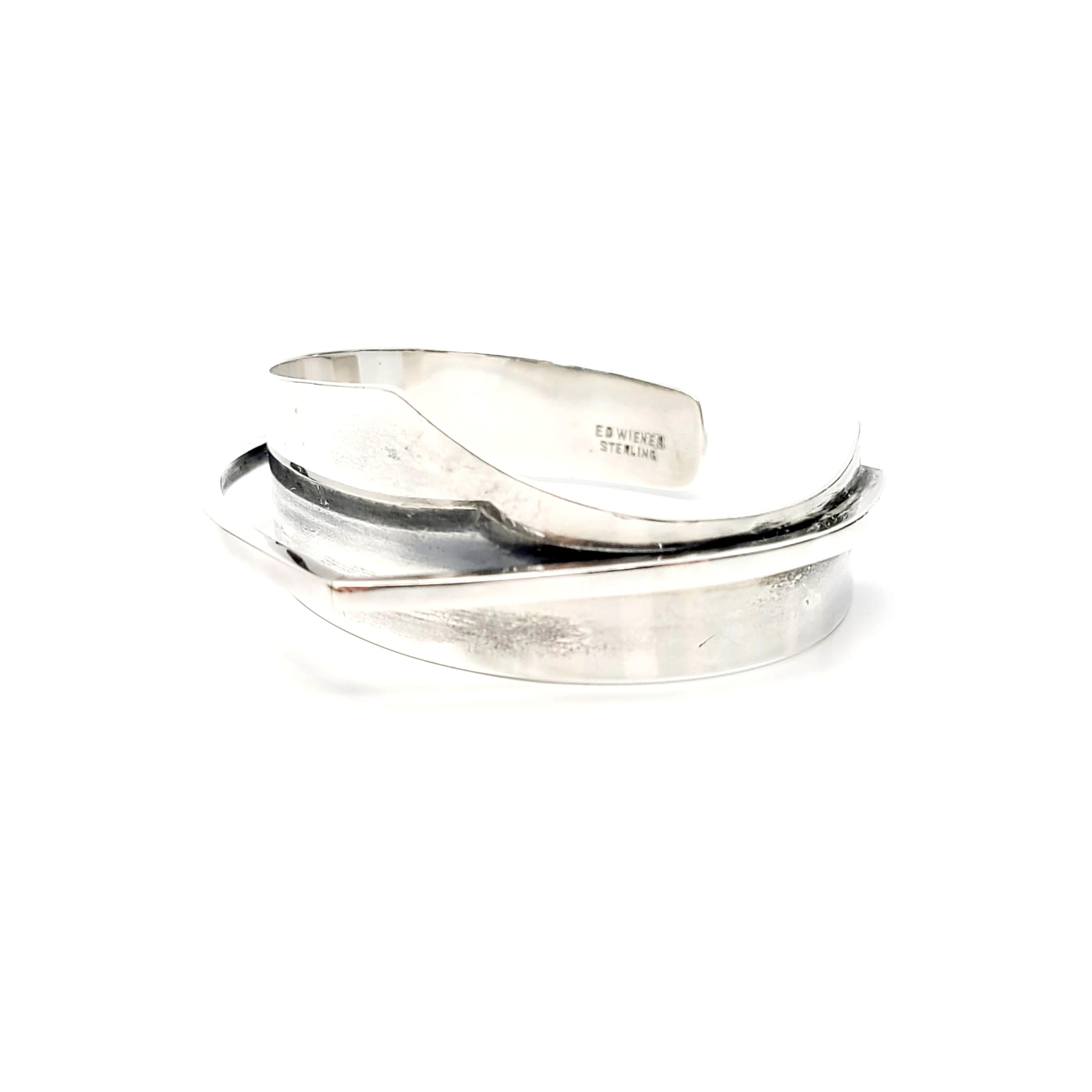 Vintage sterling silver modernist cuff bracelet by Ed Wiener, circa mid-20th Century.

Ed Wiener was a NYC based designer known for modernist, abstract and unique designs. This pieces features a bold asymmetrical design featuring a  smooth cuff with