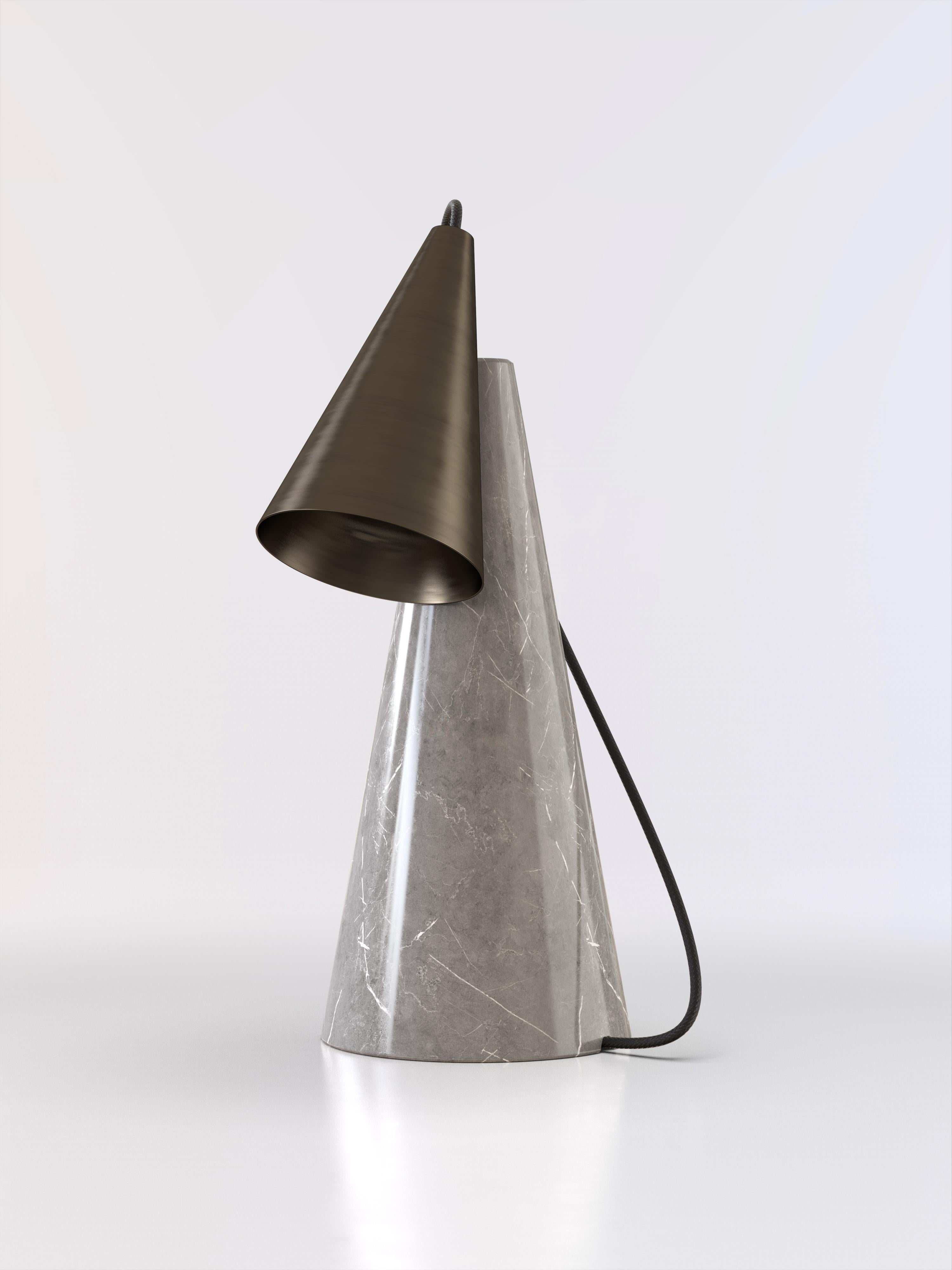 Table lamp with grey stone base and conic bronze lightshade.