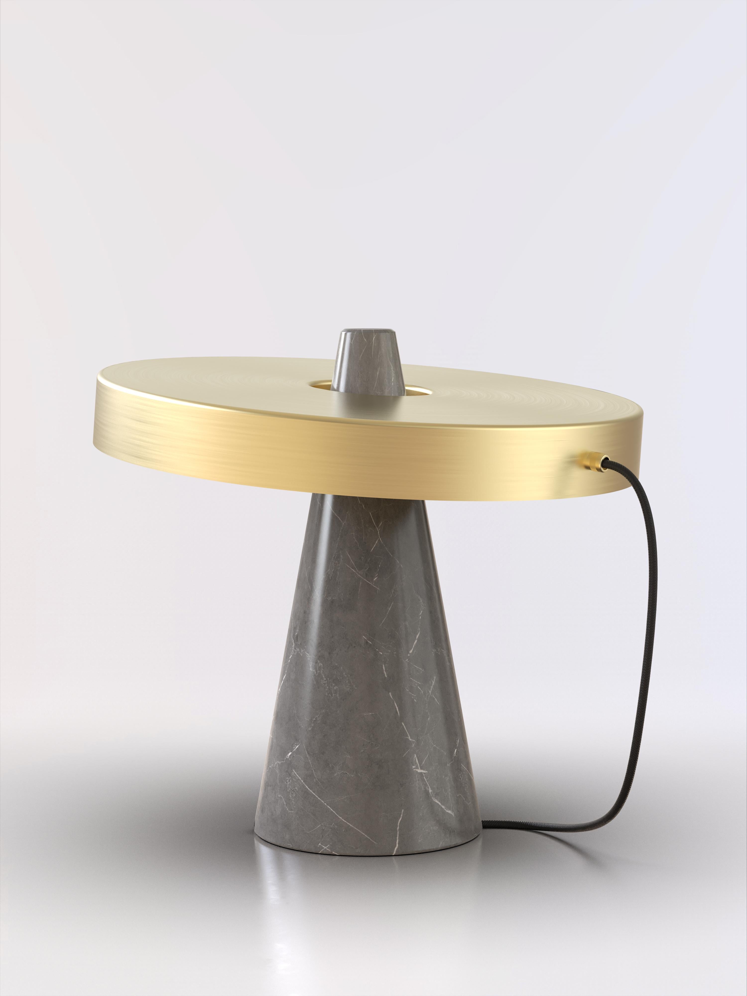 Lampe de table avec base en pierre grise et abat-jour en laiton brossé.
L'abat-jour est déconnecté de la base en pierre et peut s'incliner librement, ce qui permet de changer plusieurs fois de style.
