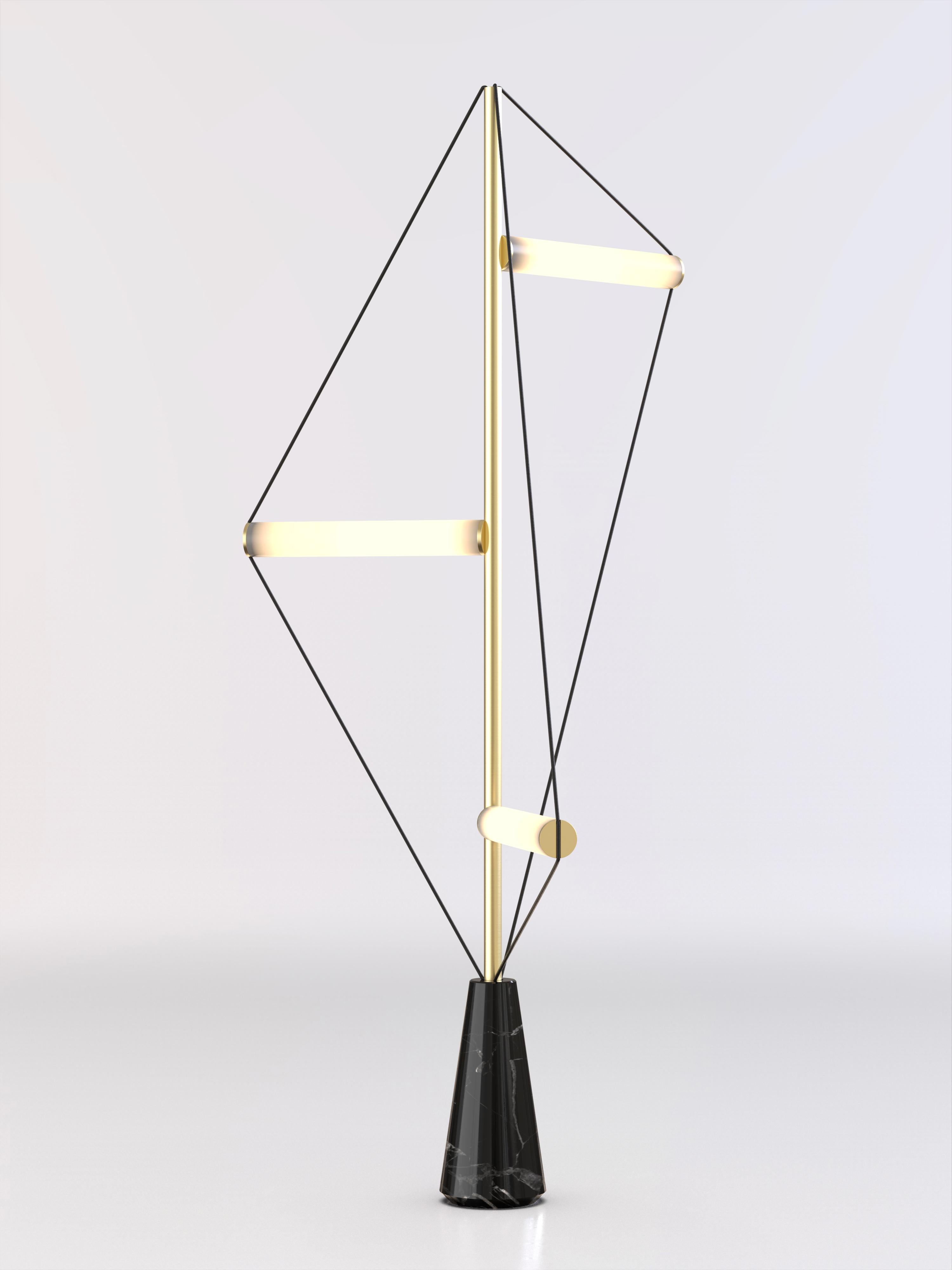Floor lamp with Marquinha black stone base, brushed brass structure and frosted light tubes.
