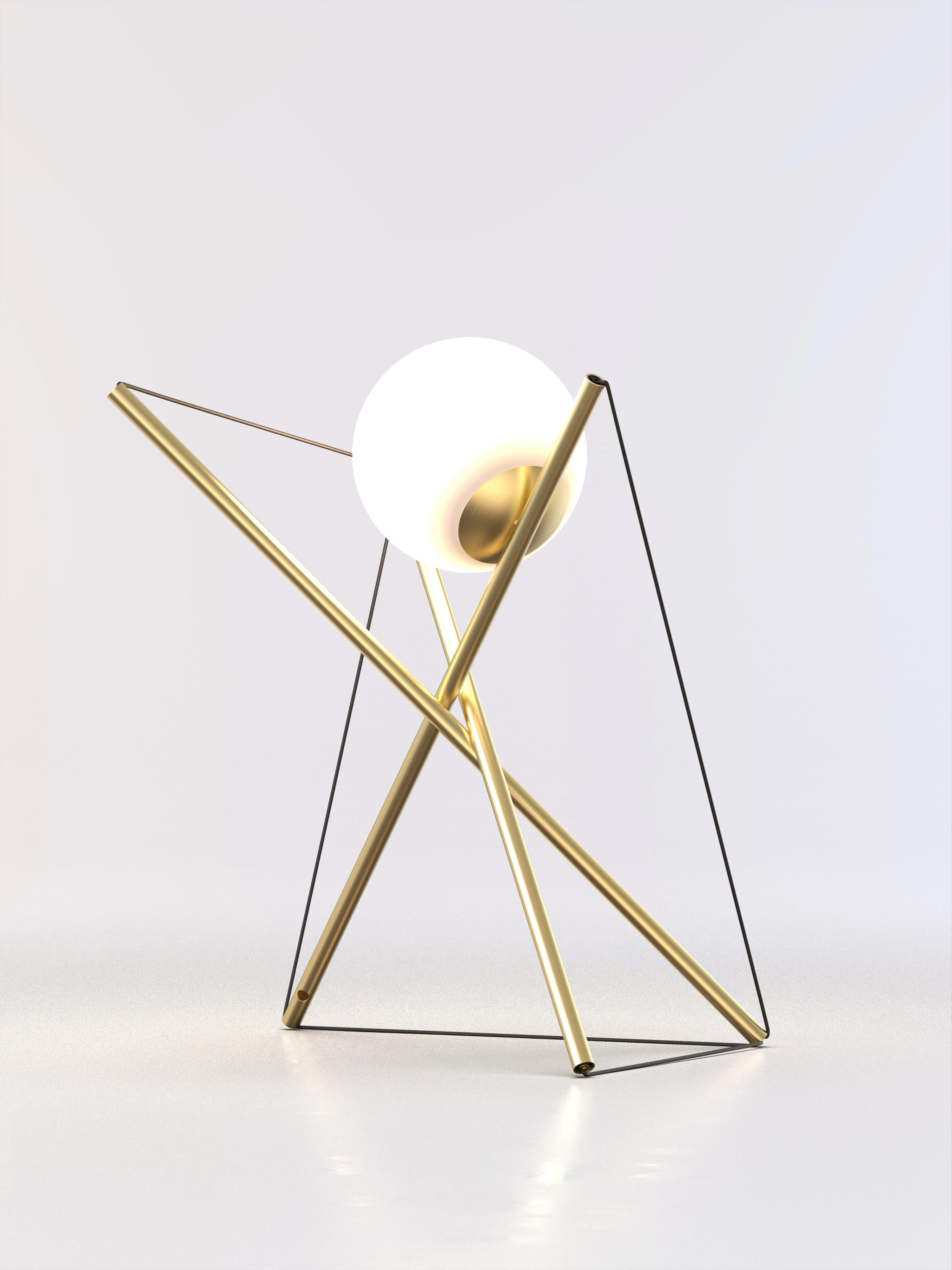 Lámpara de sobremesa con estructura de latón cepillado y esfera de luz esmerilada.