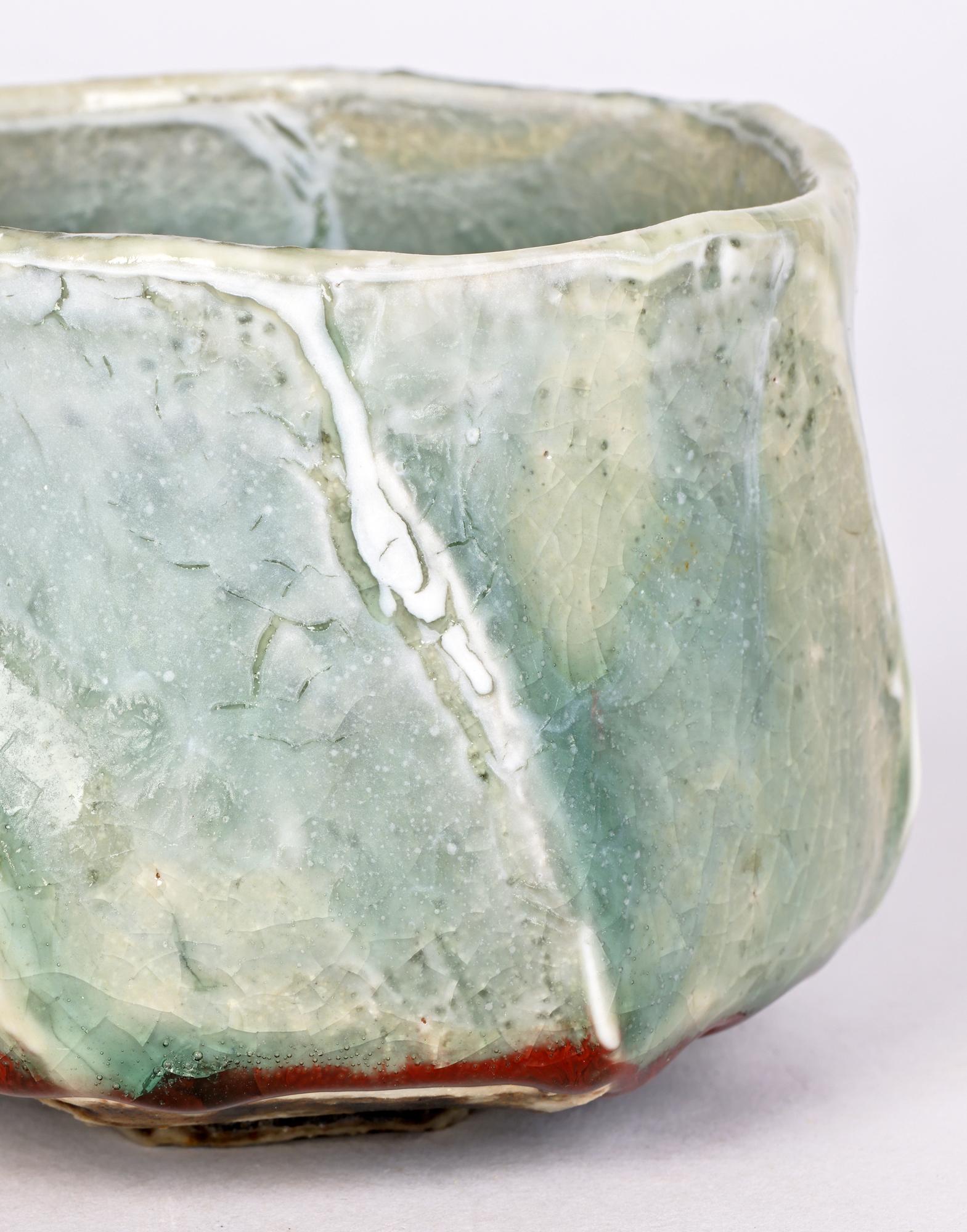 An impressive and stylish large Studio Pottery bowl decorated in celadon and shino glazes by renowned British potter Eddie Curtis and made in the 20th century. The bowl is hand crafted and stands on a narrow unglazed hexagonal foot a twisted shaped