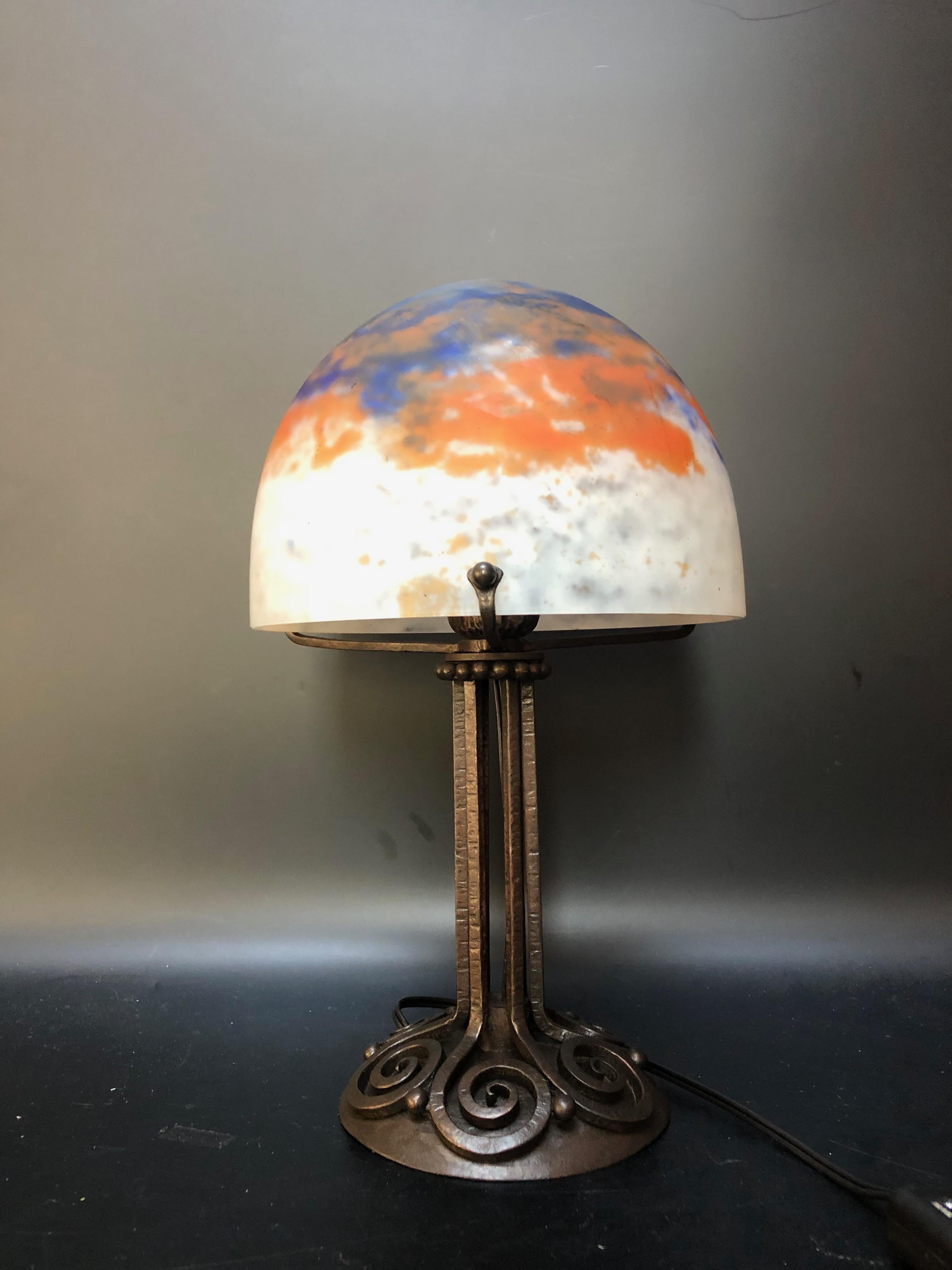 Art deco lamp circa 1925.
Wrought iron foot with spiral decoration, stamped E. Brandt.
Shell in blue and orange speckled white glass paste signed Daum Nancy France.
Electrified and in perfect condition.
Total height: 30cm
Base diameter: 11.8