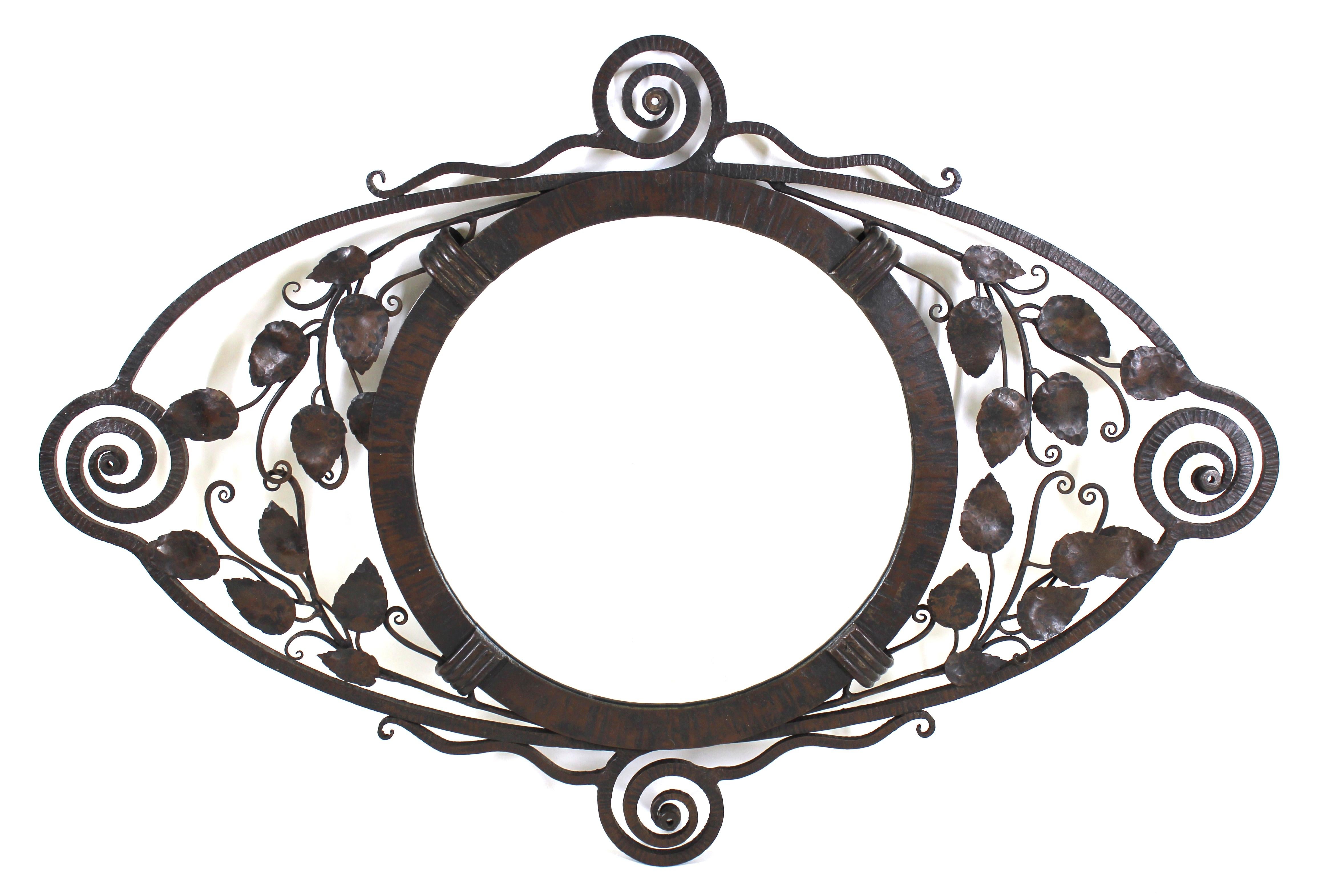 French Art Deco wrought metal wall mirror with textured ridged edge, round mirror glass and ornamental foliage and swirls, attributed to Edgar Brandt.