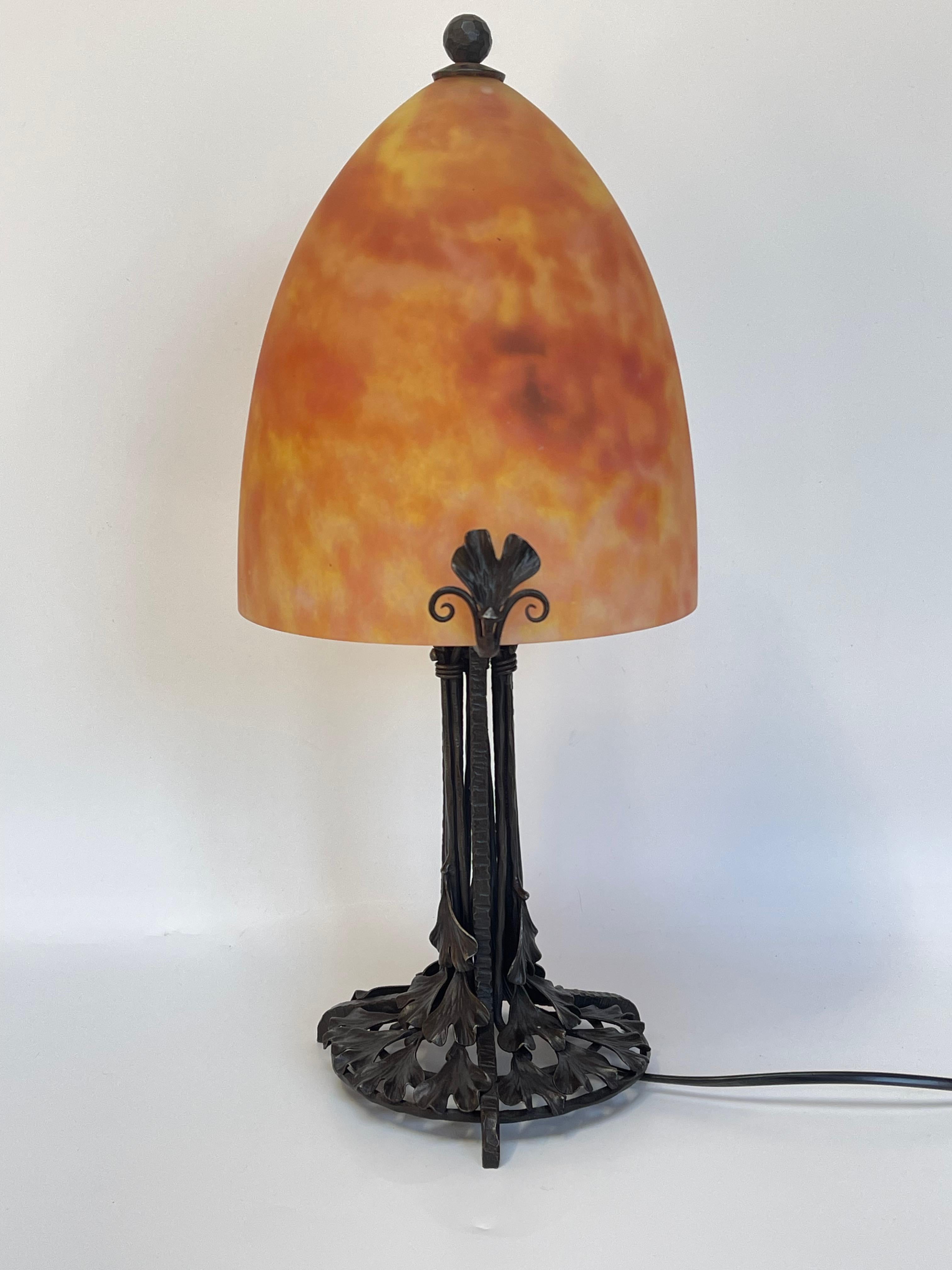 Edgar Brandt wrought iron lamp decorated with ginko biloba. 
Signed E Brandt on the support of the shell
Glass paste shell signed Daum Nancy.
In very good condition and electrified.

Total height: 46.5 cm
Foot diameter: 17 cm
Shell diameter: 20