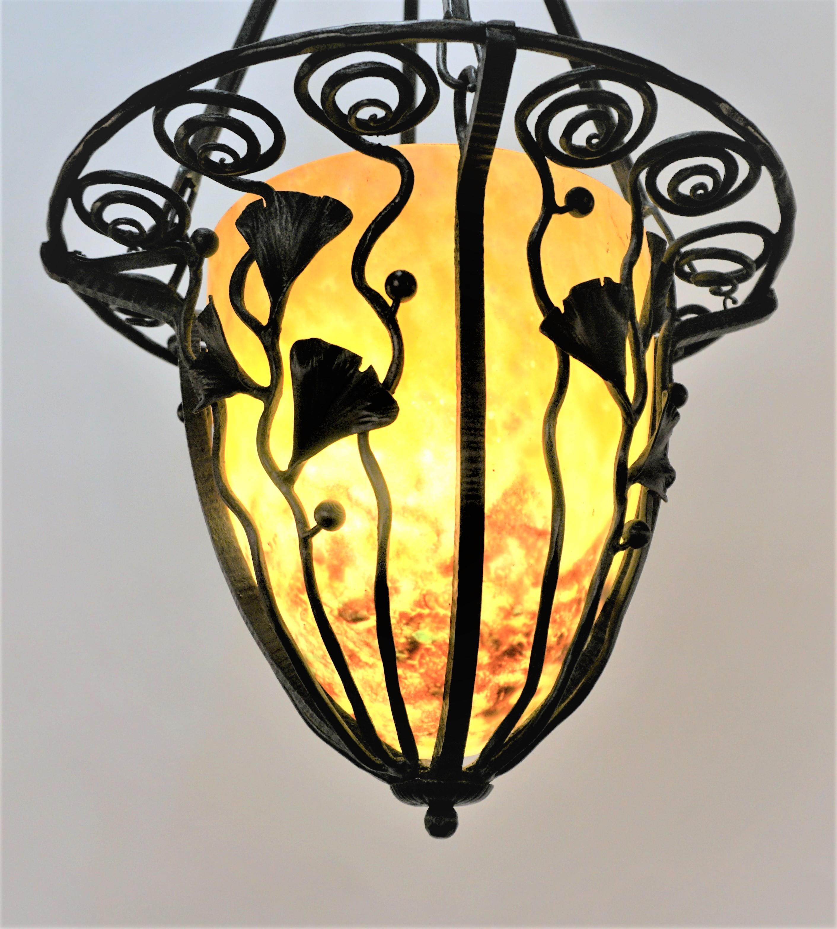 An Edgar Brandt style gingko leaf wrought iron chandelier with signed Daum Nancy glass shade.