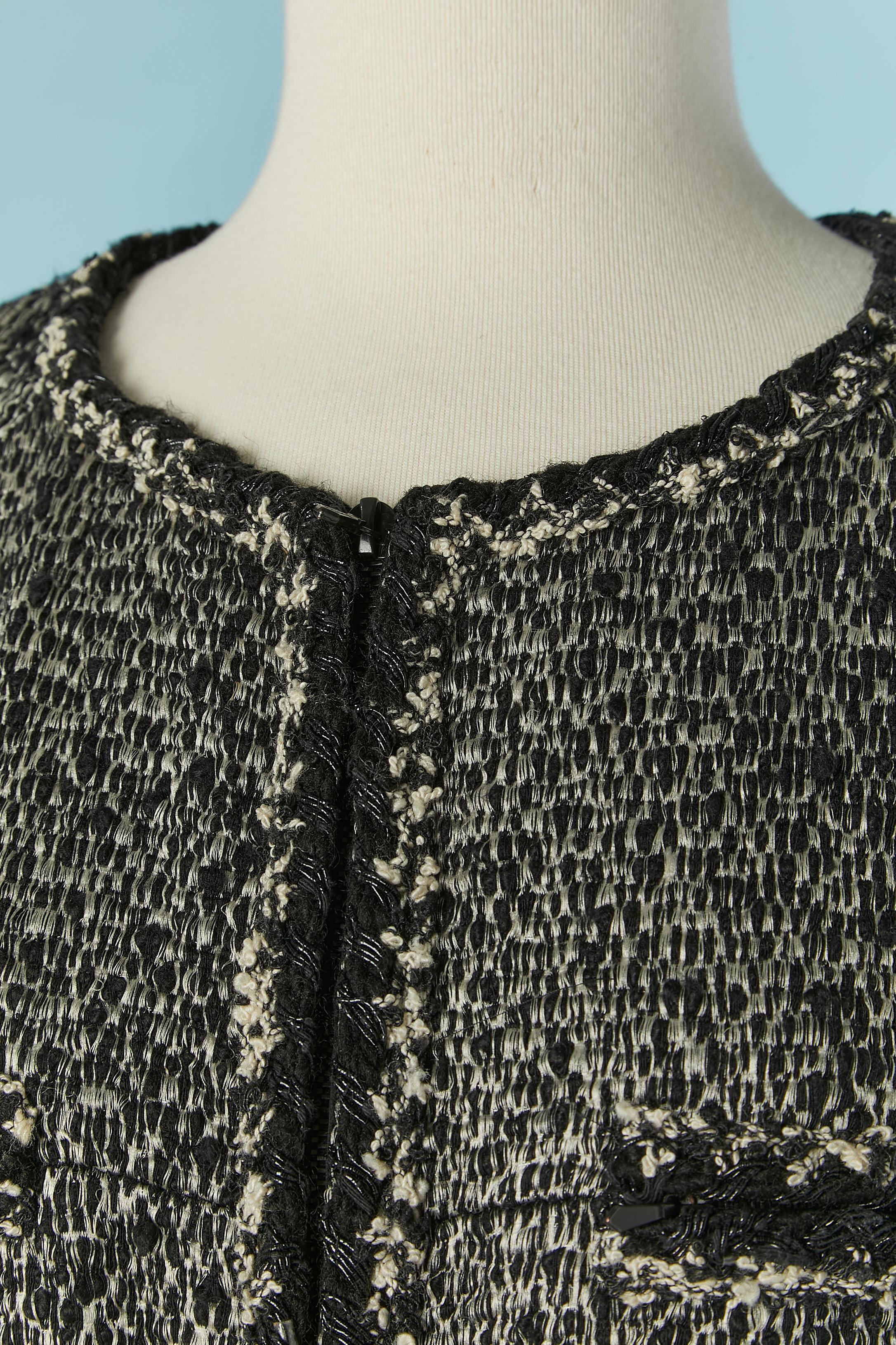 Giacca in tweed bianco e nero da un bordo all'altro. Composizione del tessuto principale: 58% lana, 29% acrilico, 9% seta, 4% nylon. Fodera in seta con marchio. Chiusura con zip al centro della parte anteriore e sulle tasche. Catena all'interno sul