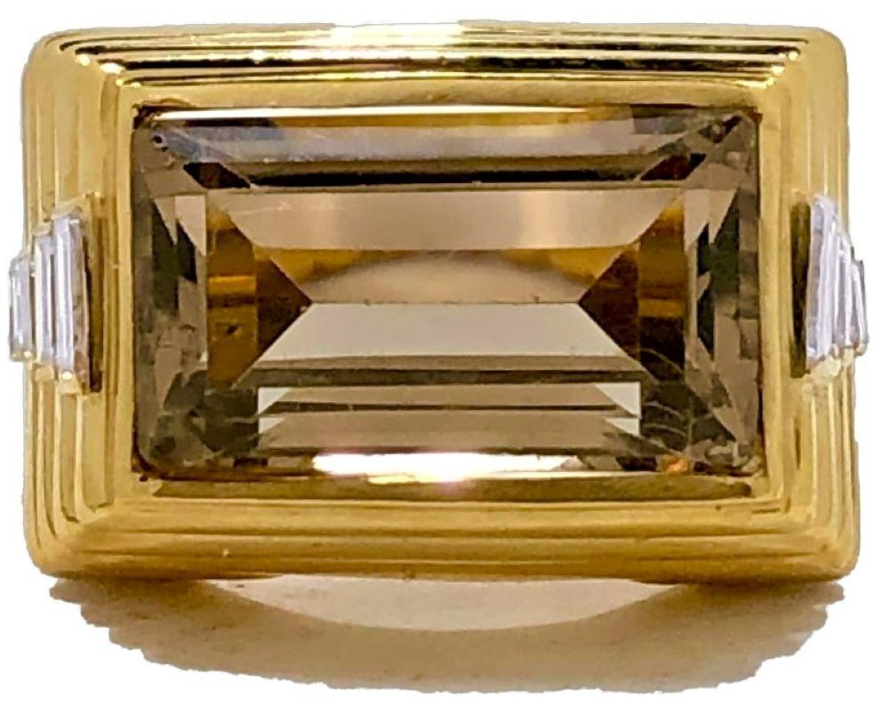 This very stylish 18k yellow gold ring is designed as a continuous cascade of horizontal fluted bands and has, at it's center one emerald cut smoky quartz measuring 5/8 inches by 3/8 inches and weighing approximately 10.00ct. On each shoulder are