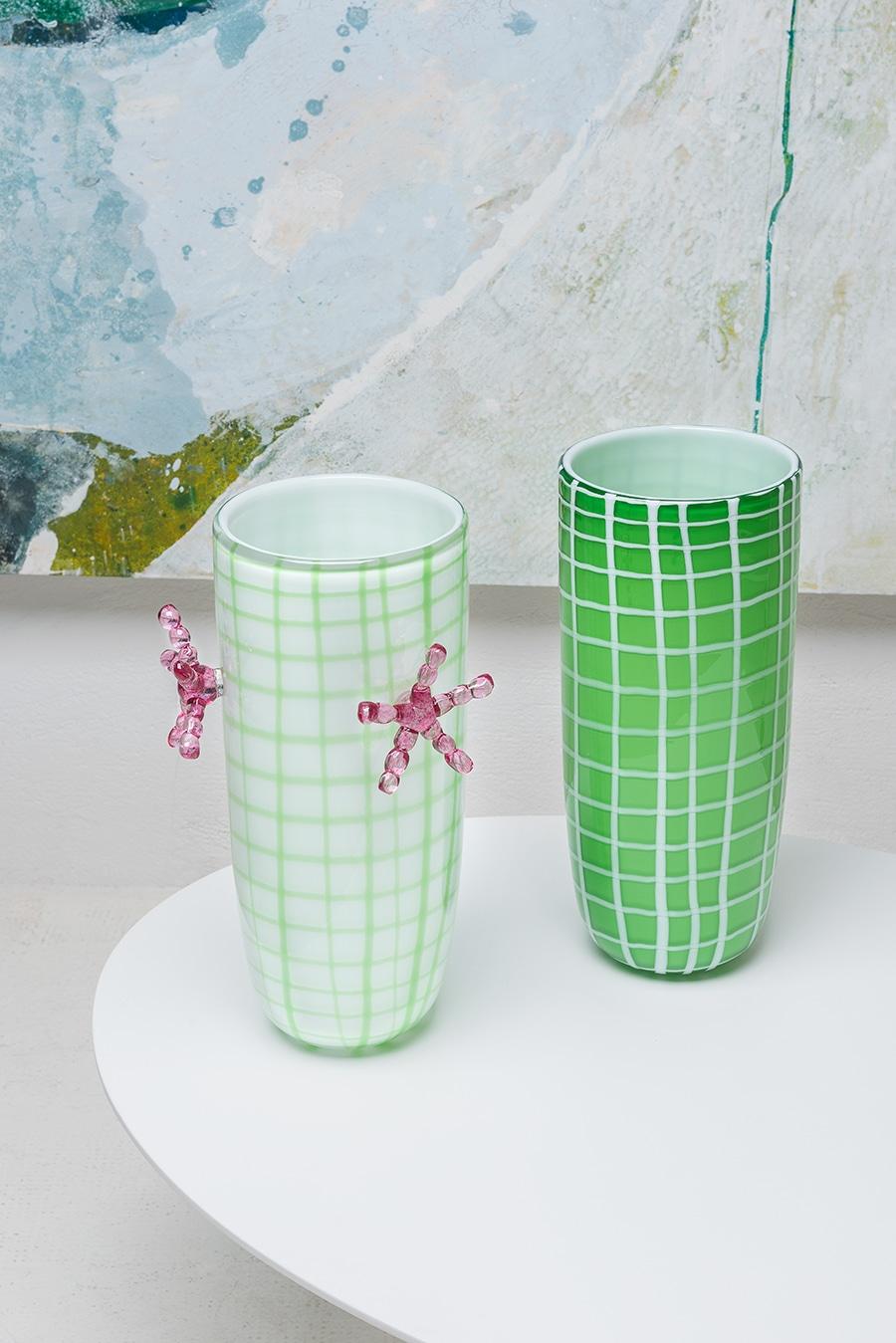 Part of a limited edition, this vase was designed by Elena Cutolo, student of legendary architect Ettore Sottsass. It was crafted of mouth-blown Murano glass and shaped in an elongated shape in white with an asymmetric net of crossing emerald green