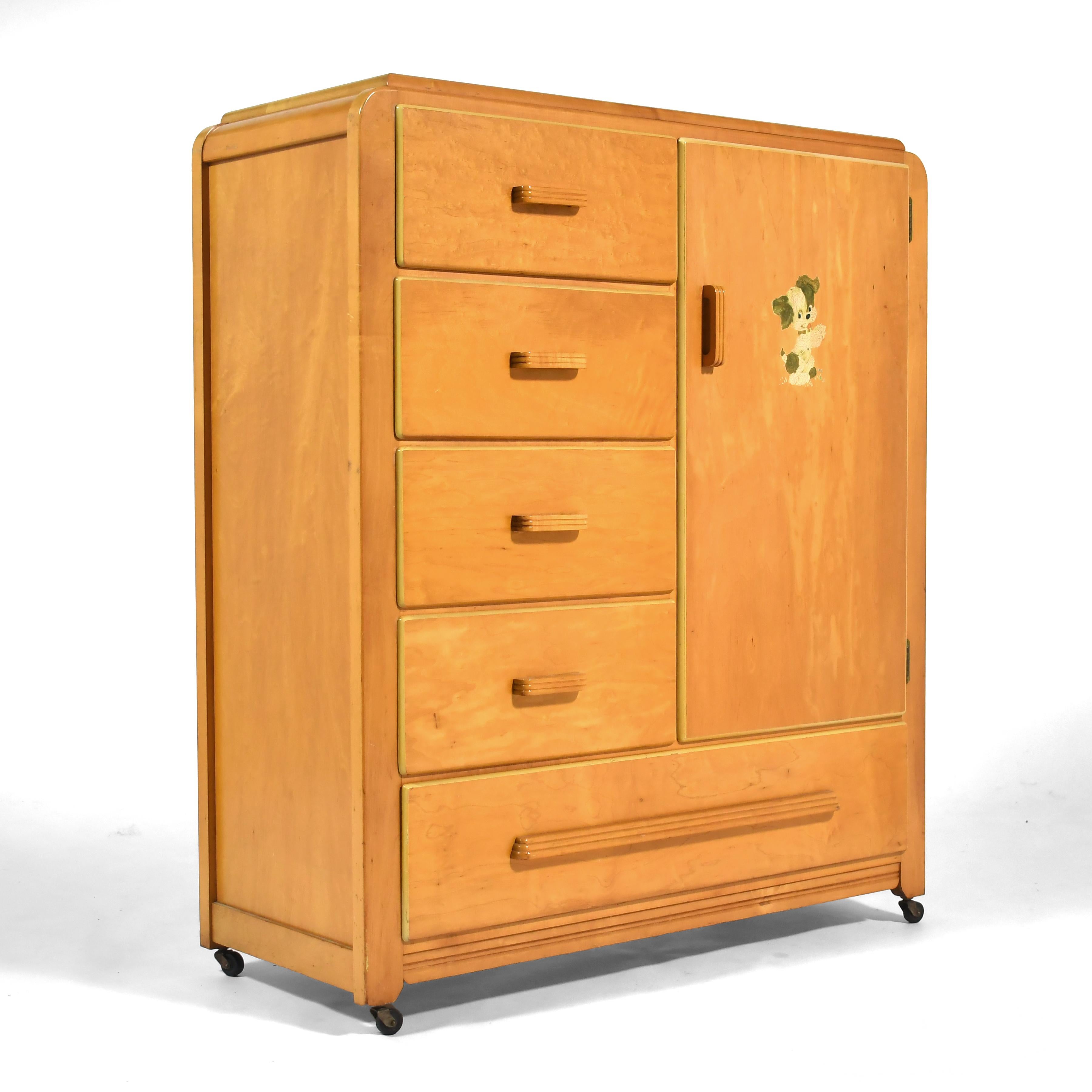This lovely little child's armoire in maple by Edison Little Folks has handsome deco style detailing and is highly functional with a bank of four drawers over a wide drawer and a compartment with a pull-out hanger rod. 

The decal of the puppy was