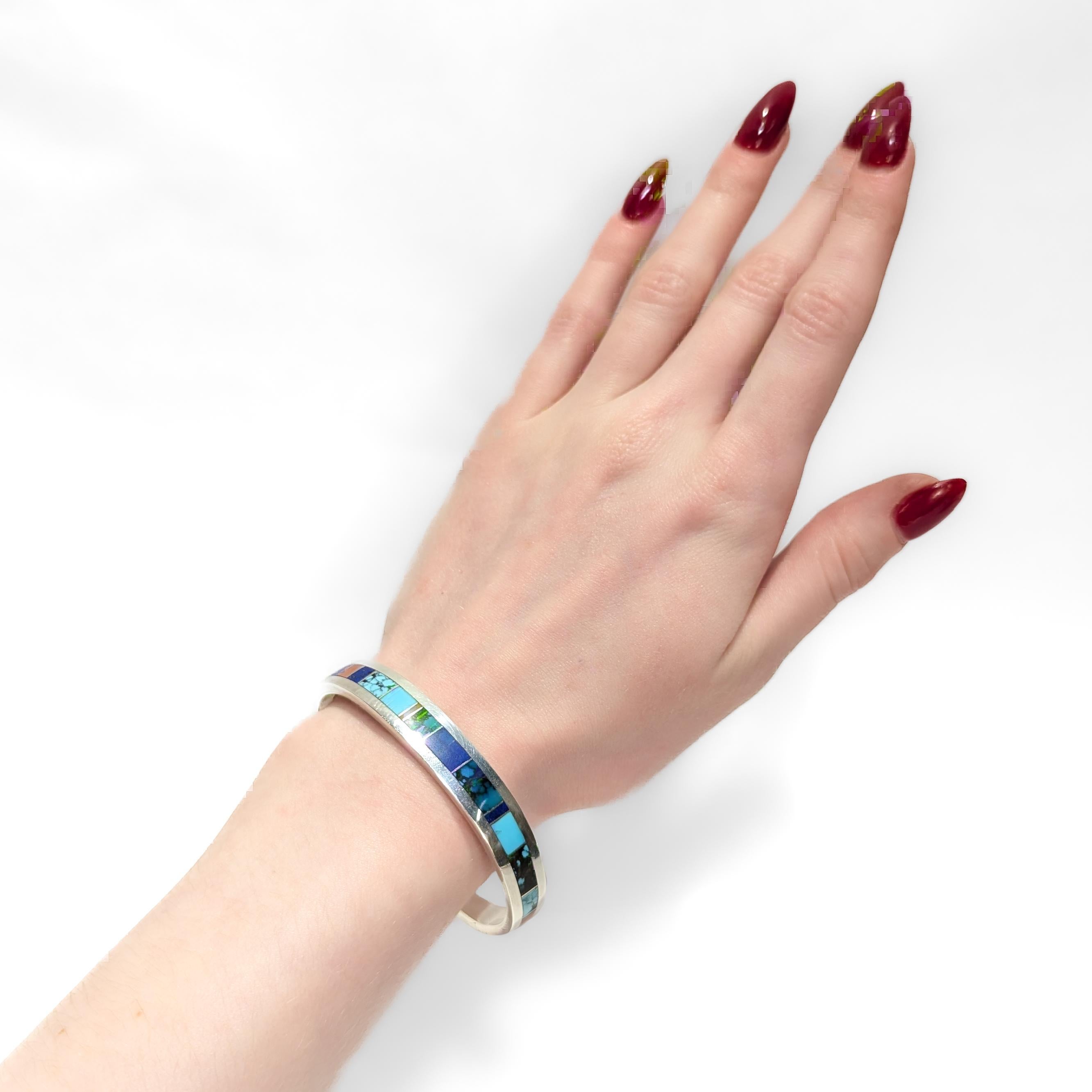 A fine Native American silver cuff bracelet.

By Edison Yazzie.

In sterling silver. 

Inlaid with Kingman turquoise, lapis, and coral, and with engraved grooves to each terminal.

Marked to the interior.

Simply a wonderful Navajo
