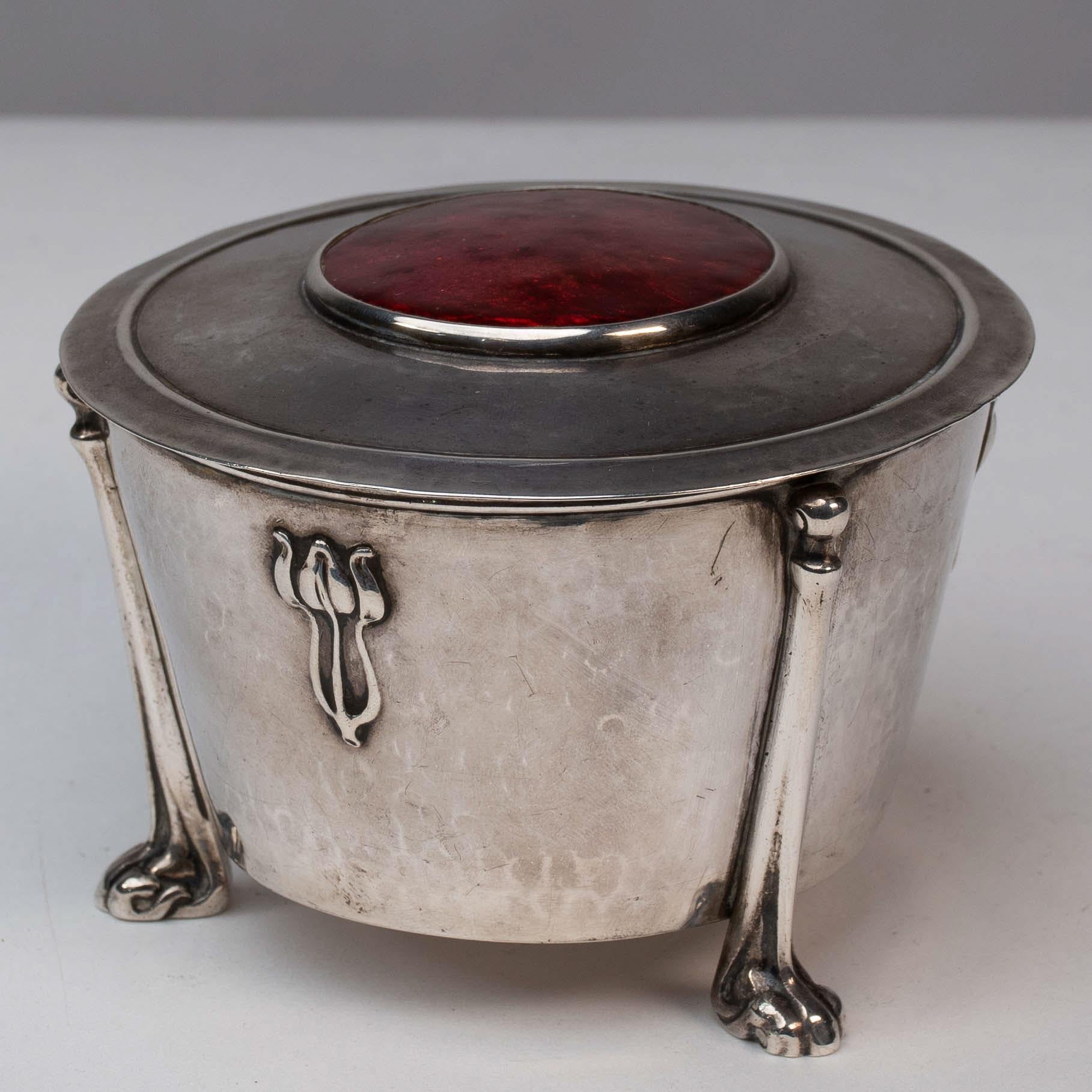 Nelson Dawson, probably made by his wife Edith Dawson.
A rare Arts & Crafts silver bowl with a red enamel lid and a particular E Dawson floral decoration to the sides, on four elongated footed legs that attach to the entire sides, again typical of