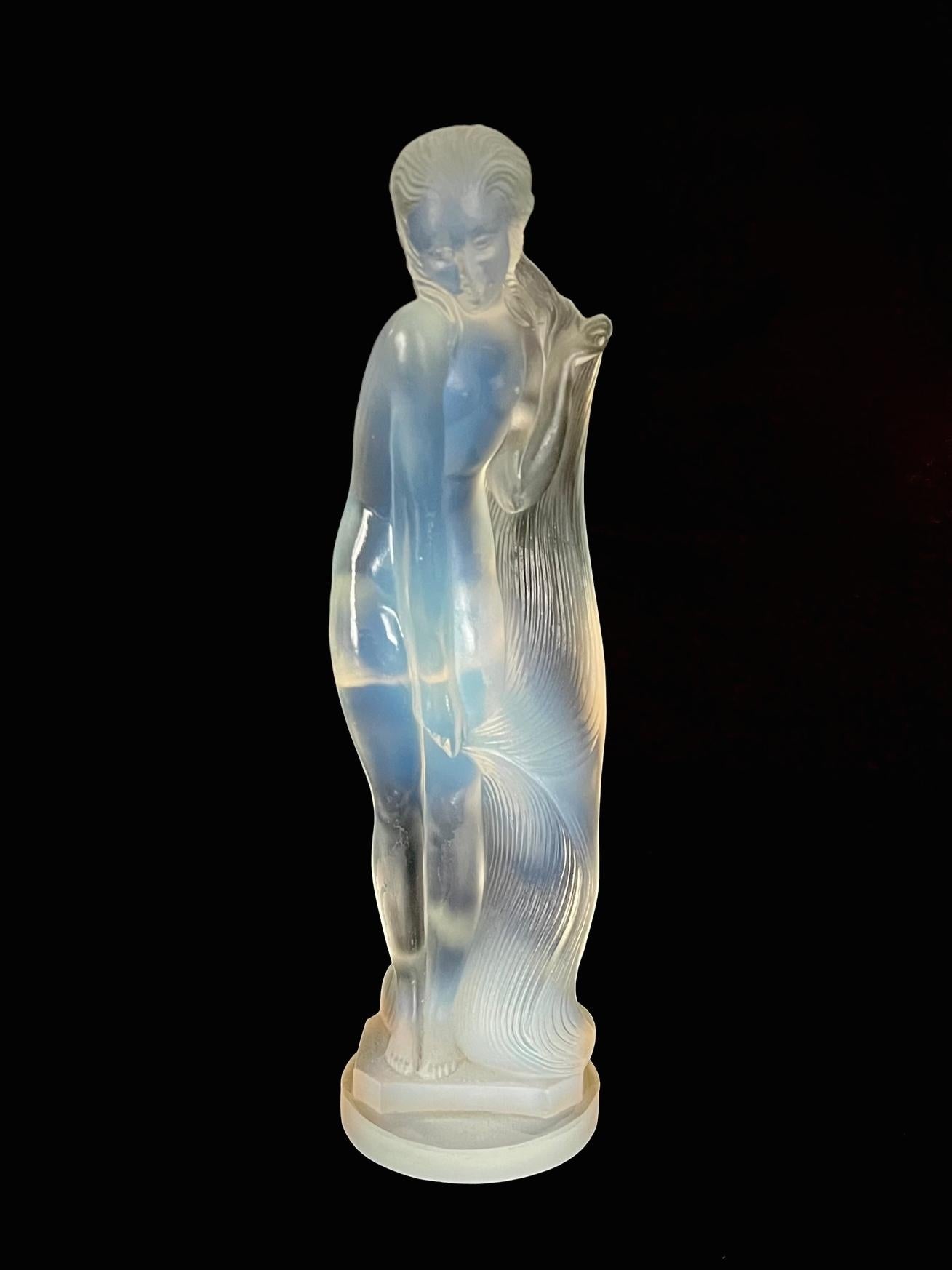 An Art Déco opalescent glass statuette modelled as a nude draping her hair around her body. 
Designed for Edmond Etling et Cie by sculptor Lucile Sevin circa 1932.
Moulded mark 