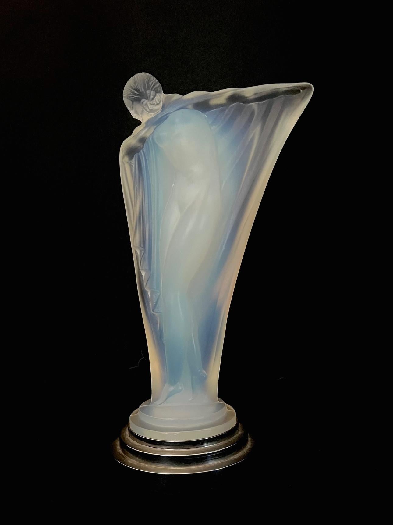 An Art Déco opalescent glass statuette of a draped nude with her arm outstretched. Mounted on a stepped nickeled base. Signed 
