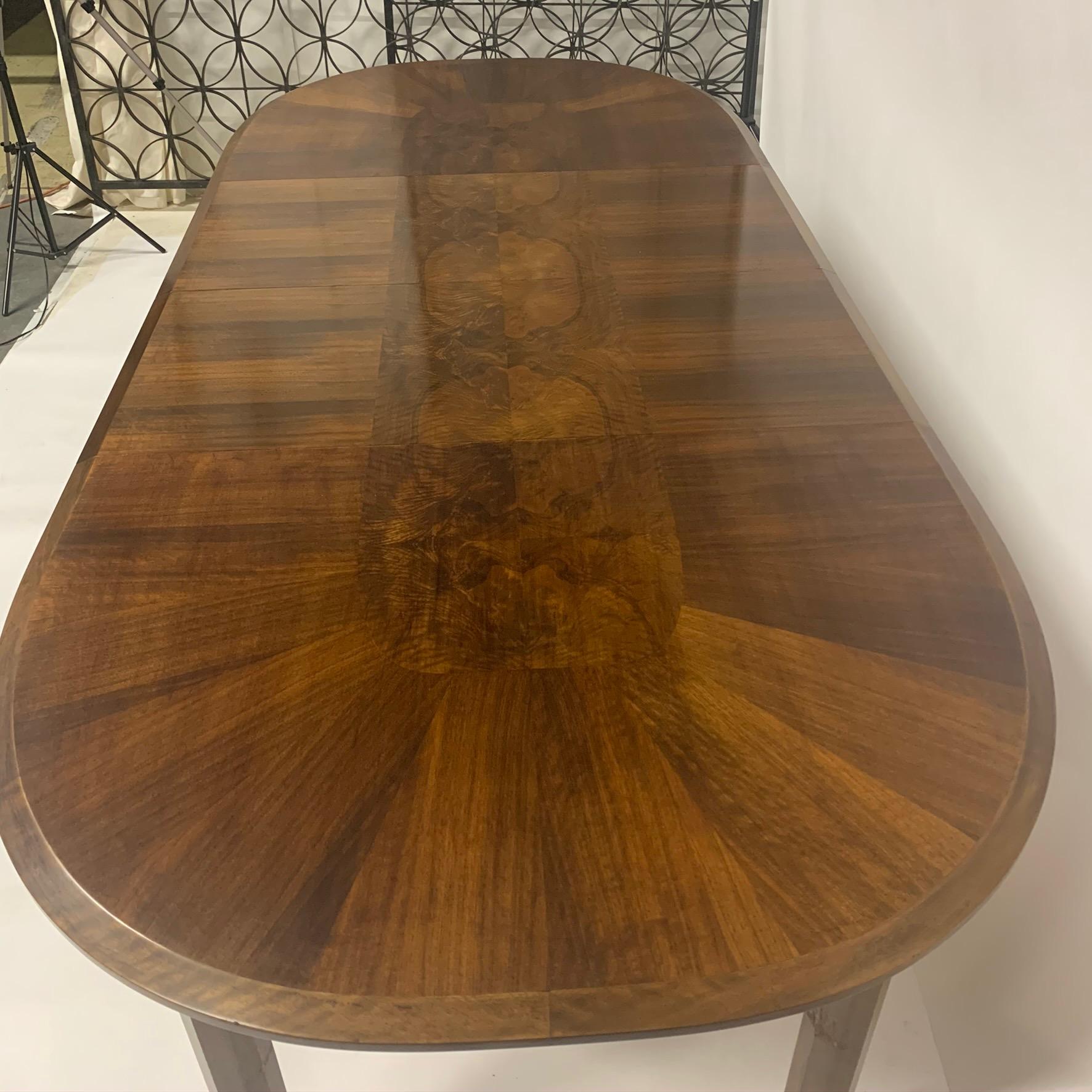 Absolutely stunning and hard to find Edmond J. Spence Dining table of mixed woods. The subtle detailing on this piece is incredible. The tabletop has a burled inlaid center detail with a walnut decorative design. The legs appear to be solid