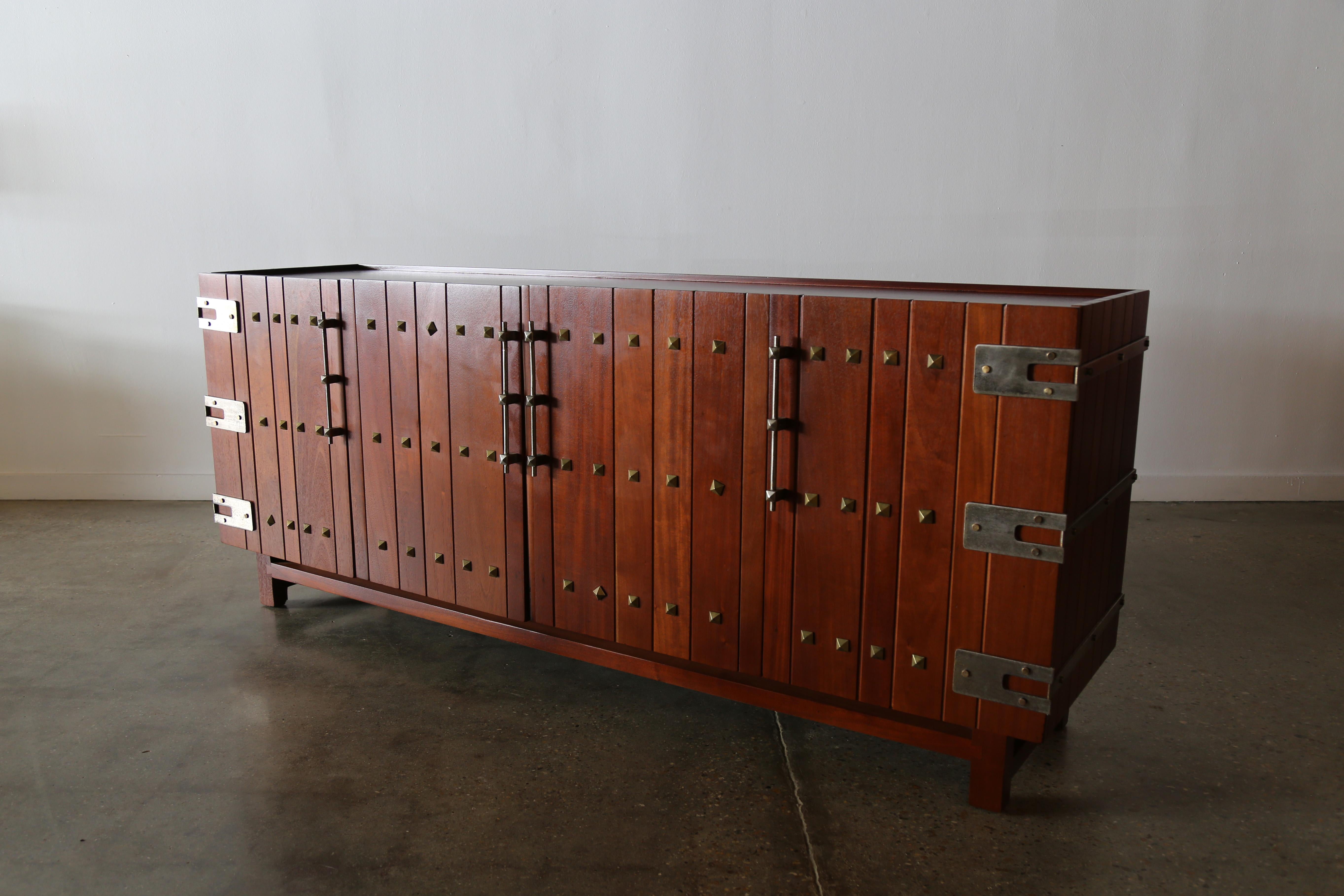 Credenza Virrey a quattro ante in mogano massiccio degli anni '50 disegnata da Edmond Spence per Industria Meublera Mexico. Caratterizzato da borchie in ottone e da una minuteria argentata a contrasto.

Dietro ogni anta laterale, un vassoio