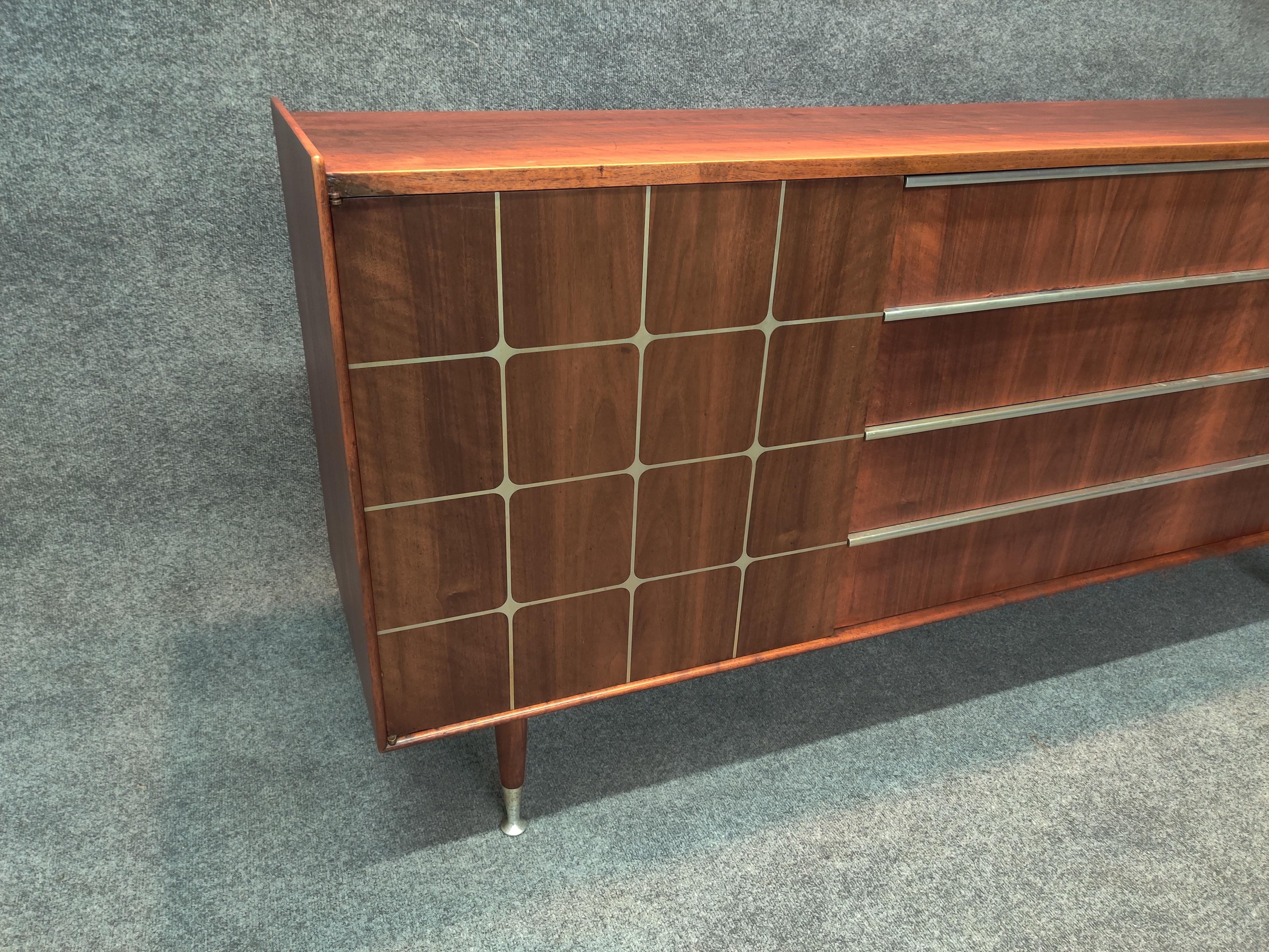 A stunning vintage sideboard, featuring a warm rubbed satin finish on book-matched walnut graining, slender aluminum handles and inlaid aluminum decorative grid. Tapered legs are quintessential in designer Edmond Spence's storage series. With style