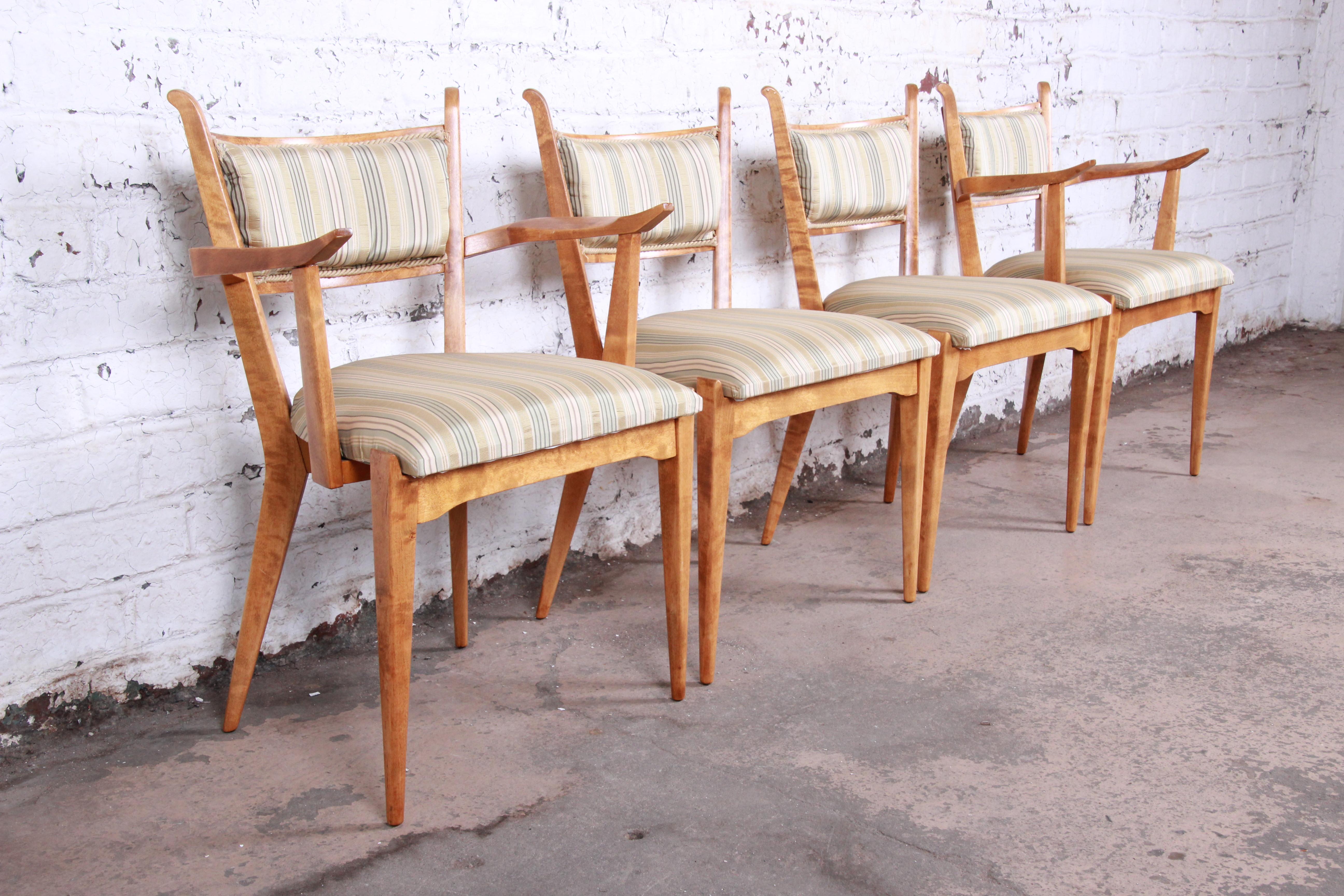 An exceptional set of four midcentury Swedish modern dining chairs designed by Edmond Spence. The set includes two captain armchairs and two side chairs. The chairs feature sleek Scandinavian design with stunning sculpted solid tiger maple frames.