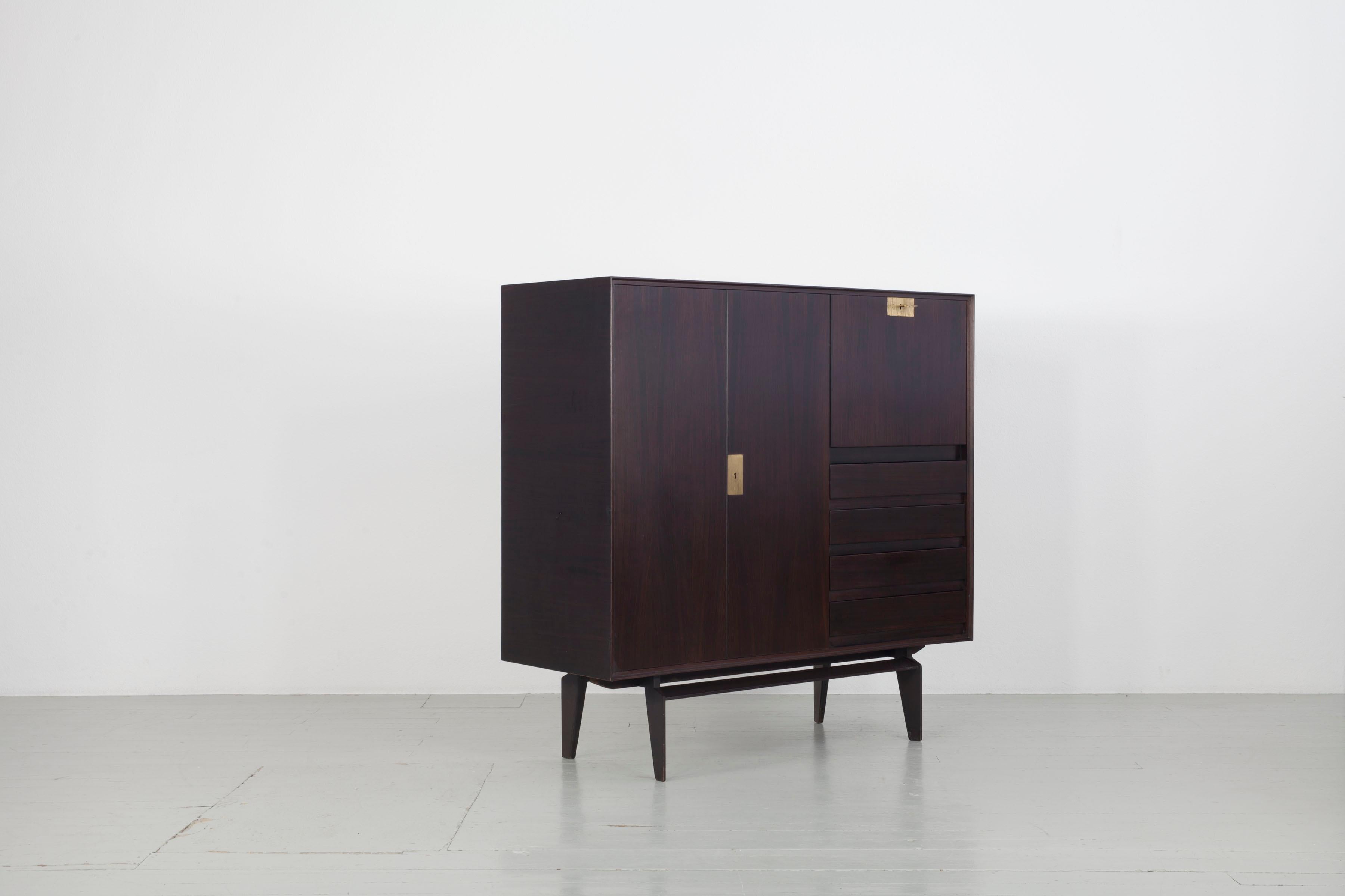 Edmondo Palutari Dassi highboard
This sideboard has been crafted with Rosewood and brass detailing. The drop-leaf door on the right hand side allows the sideboard to also function as a secretaire. The versatile sideboard offers plenty of room for