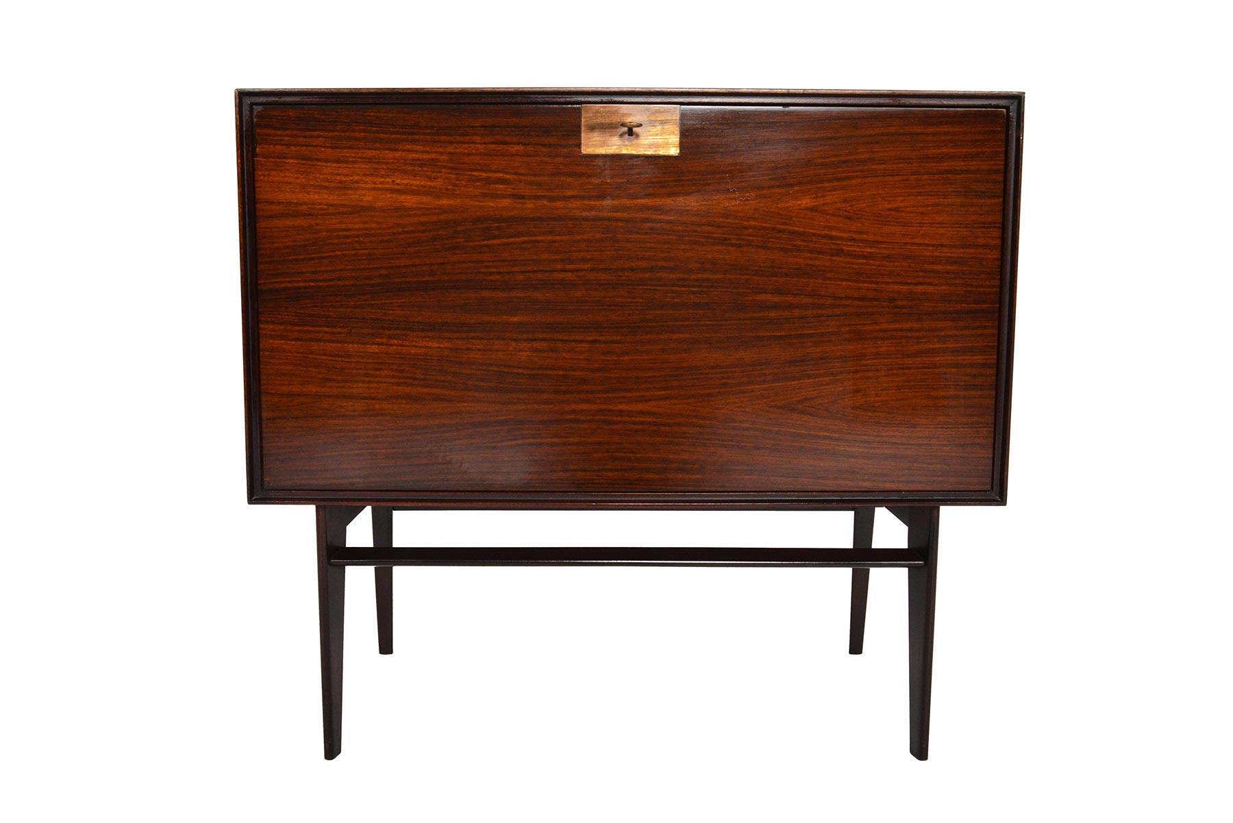 This small Italian modern rosewood chest was designed by Edmoudo Palutari for Vittorio Dassi in the 1950s. Sculpted corners frame a drop down door. Interior is outfitted with two bays and an adjustable shelf. The case stands on beautifully sculpted