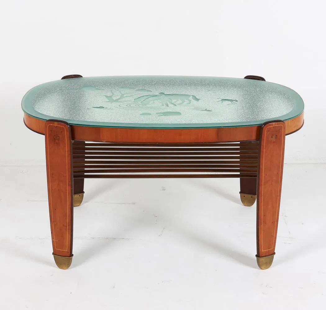 Chapa de nogal. Tapa de cristal con diseño esmerilado, que representa una escena de bosque. Pies con tapa de latón. Danés, circa 1930's.Dimensiones: Alto 22