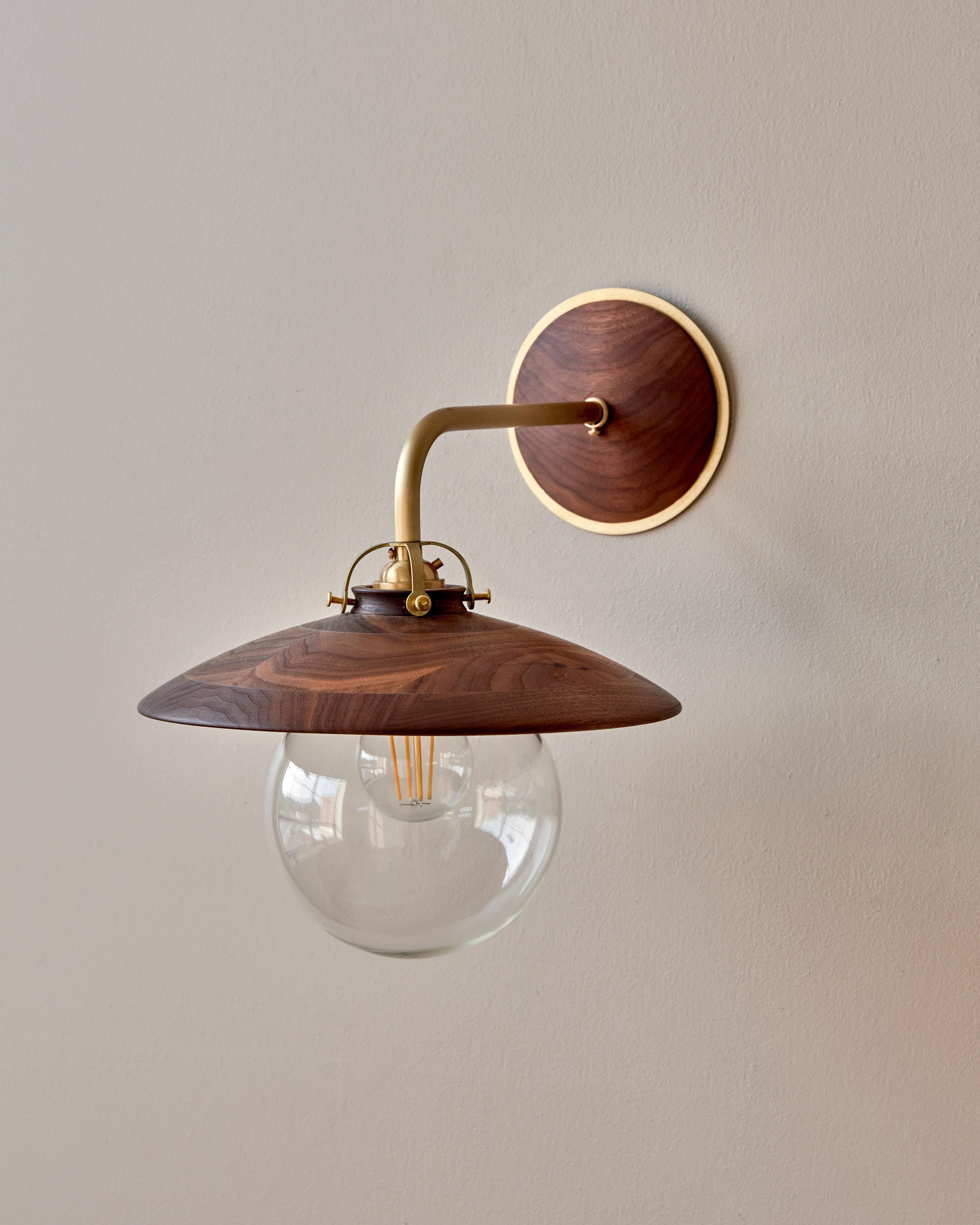 The Edmund sconce adopts the charismatic details from our beloved Edmund Pendant with its distinctive and charming shape. The hand-turned shade and oversized clear globe create a playful Silhouette while delicate cut brass fittings and hardware are