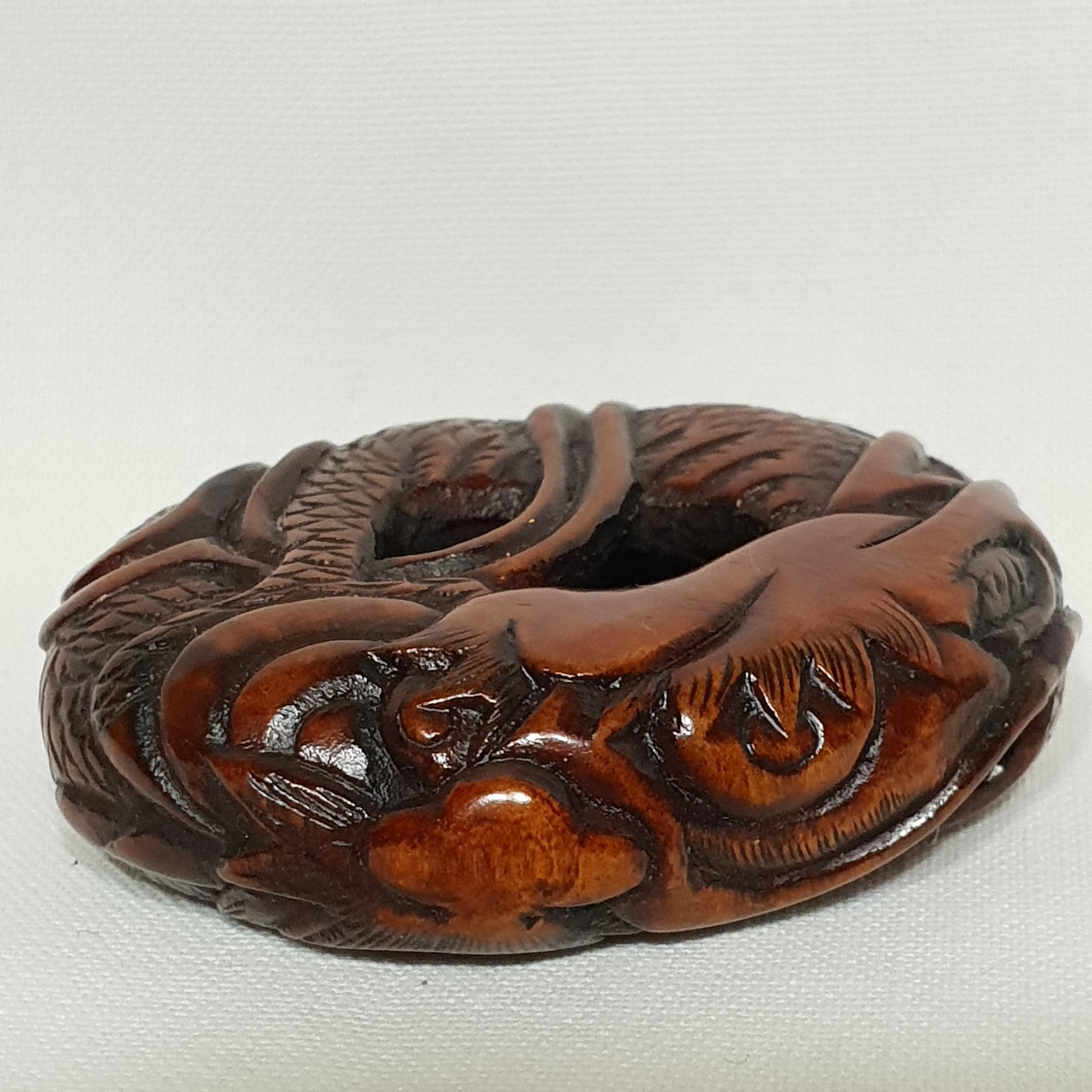 An Edo period wood netsuke in the form of Coiled Dragon
the dragon is the simbol of the protection of the sacred jewel of Buddha.
We can indeed see in the refined stylized representation the jewel held by a claw near the head of dragon.
