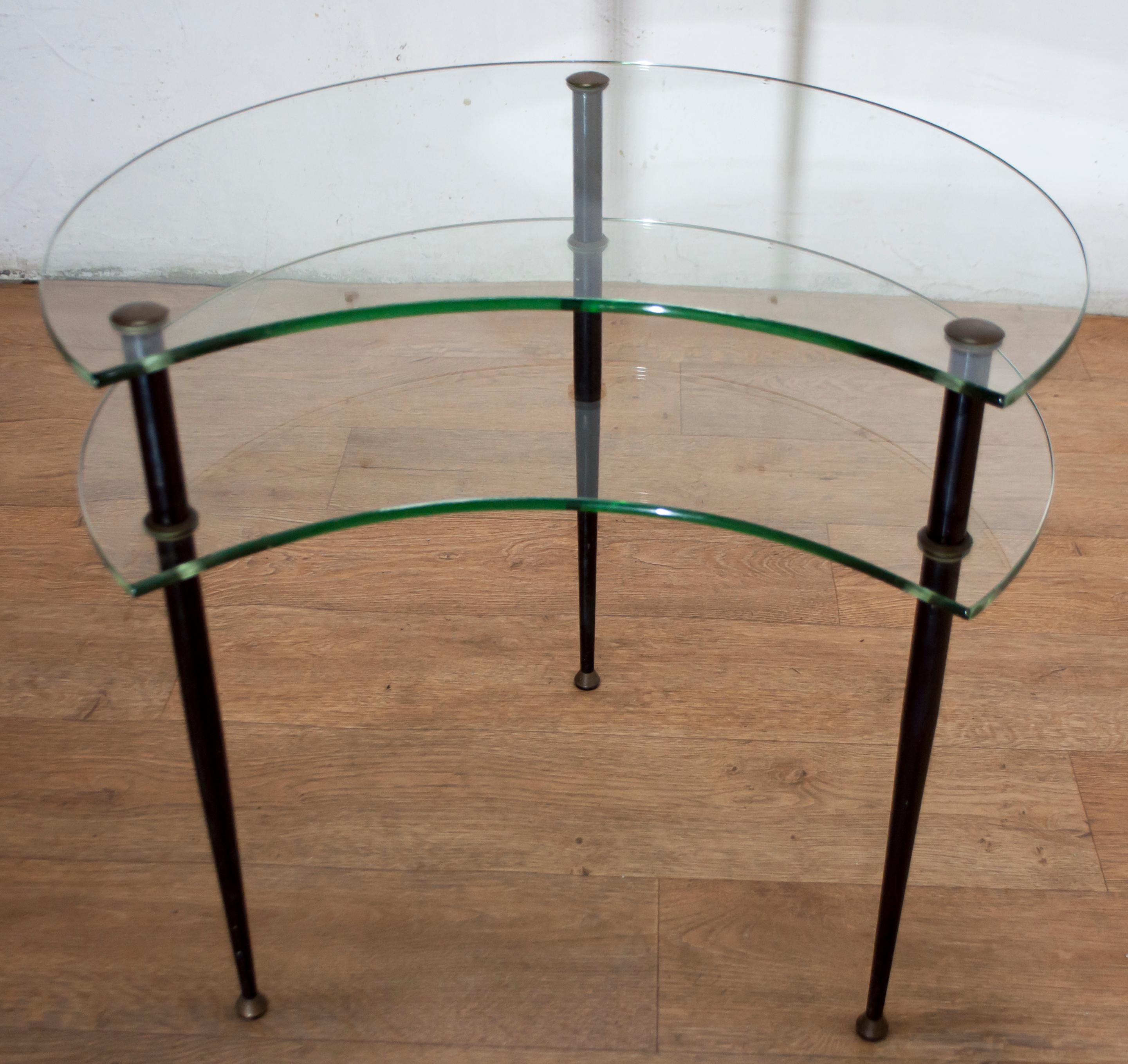This coffee table was designed by Edoardo Paoli around 1955 and is made of lacquered brass and tempered glass and was produced by Vitrex. It has two half-moon glass tops on three black lacquered brass legs.

