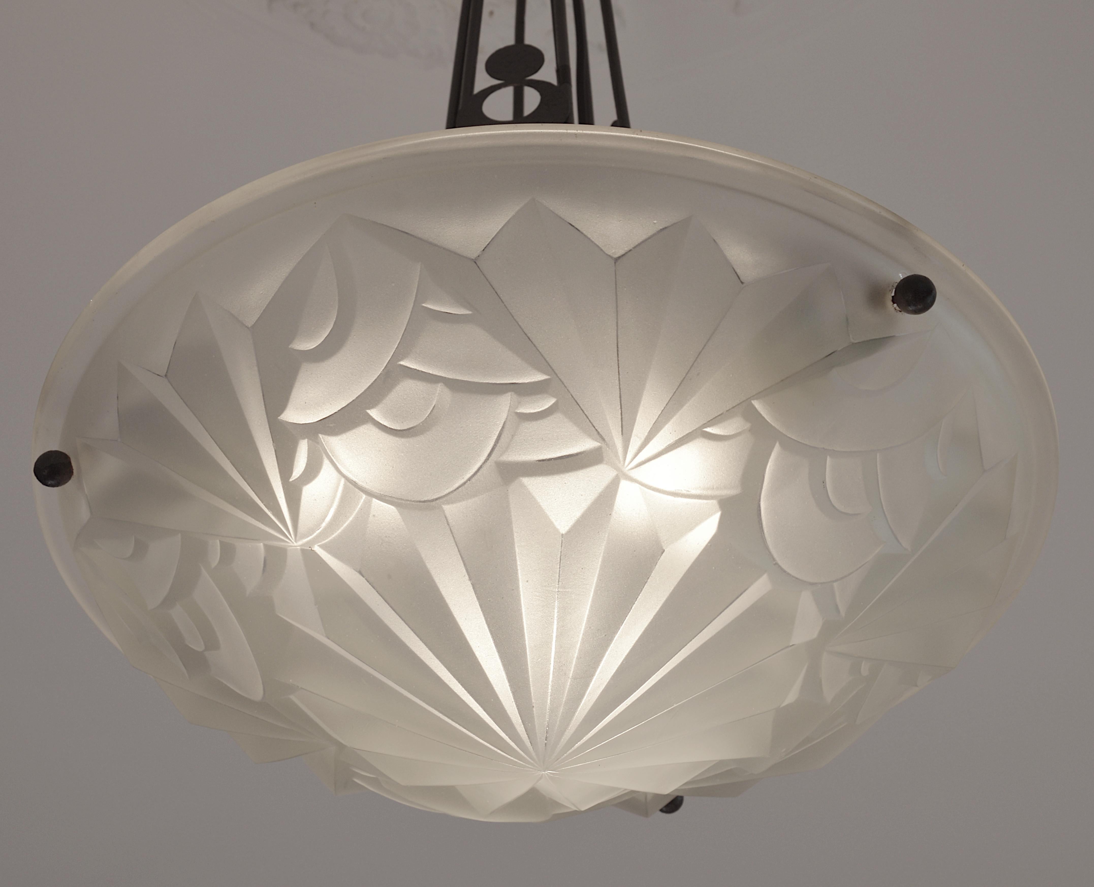 Wide French Art Deco pendant chandelier by Edouard Cazaux at Degue's, France, 1928-1930. Wide and thick white (slightly yellow) frosted glass shade with a stylized floral pattern with sharpen edges typical of the Cazaux's work. The metal frame shows