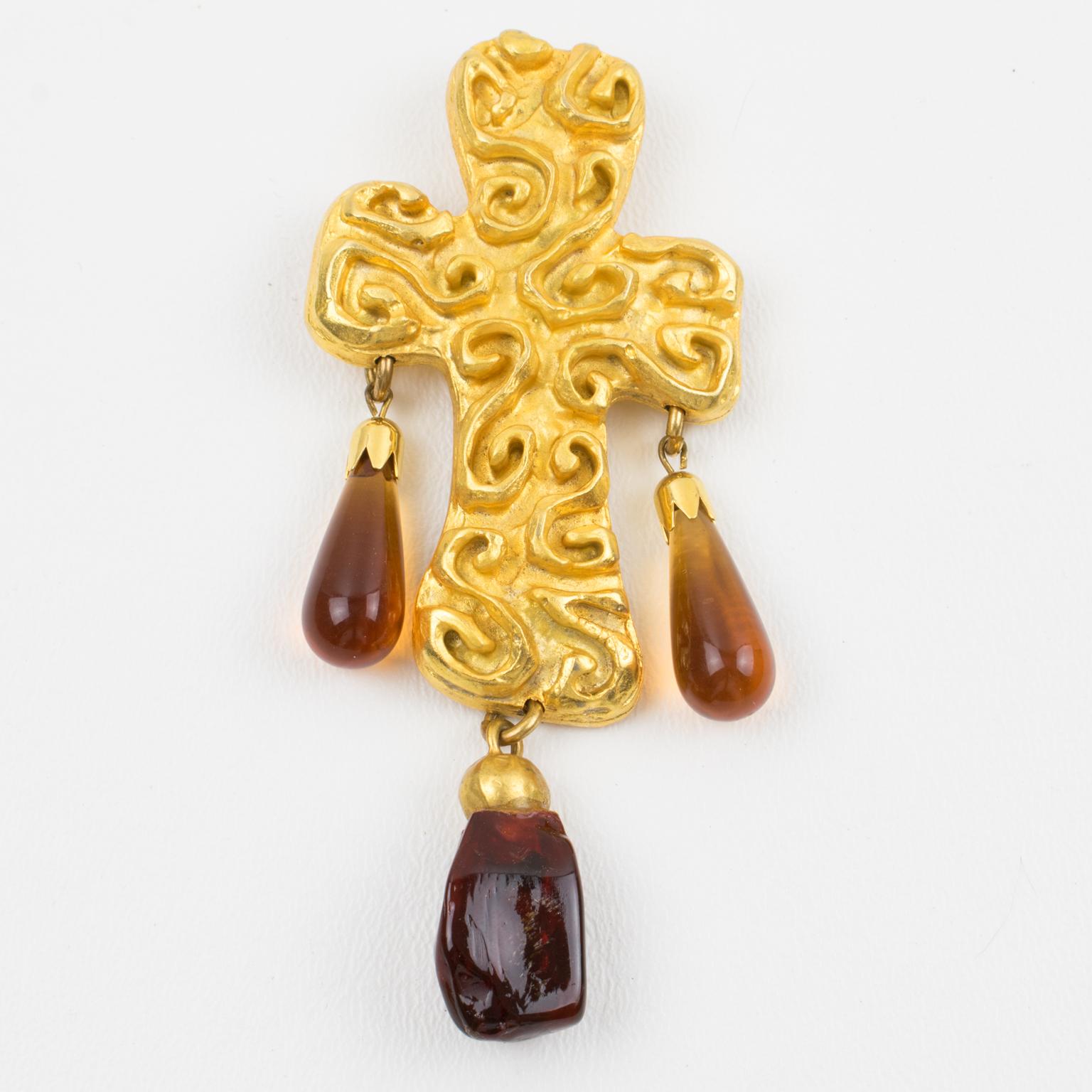 An elegant 1980s oversized cross-pin brooch created by French designer Edouard Rambaud, Paris. 
Features a byzantine-inspired design with a gilt metal cross-shaped element all textured and carved, and ornate with dangling resin drop charm cabochons