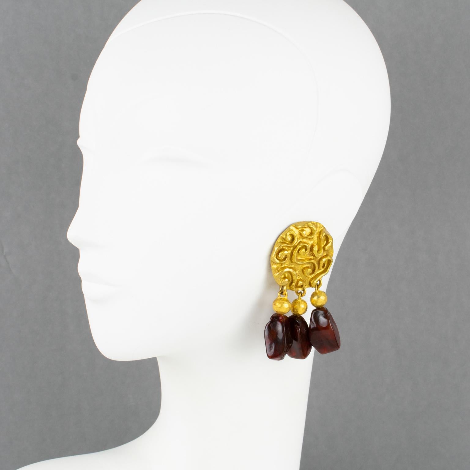 Superbes boucles d'oreilles à clip surdimensionnées des années 1980 créées par le designer français Edouard Rambaud, Paris. Elles présentent un design d'inspiration byzantine avec un élément en métal doré de forme ronde, entièrement texturé et