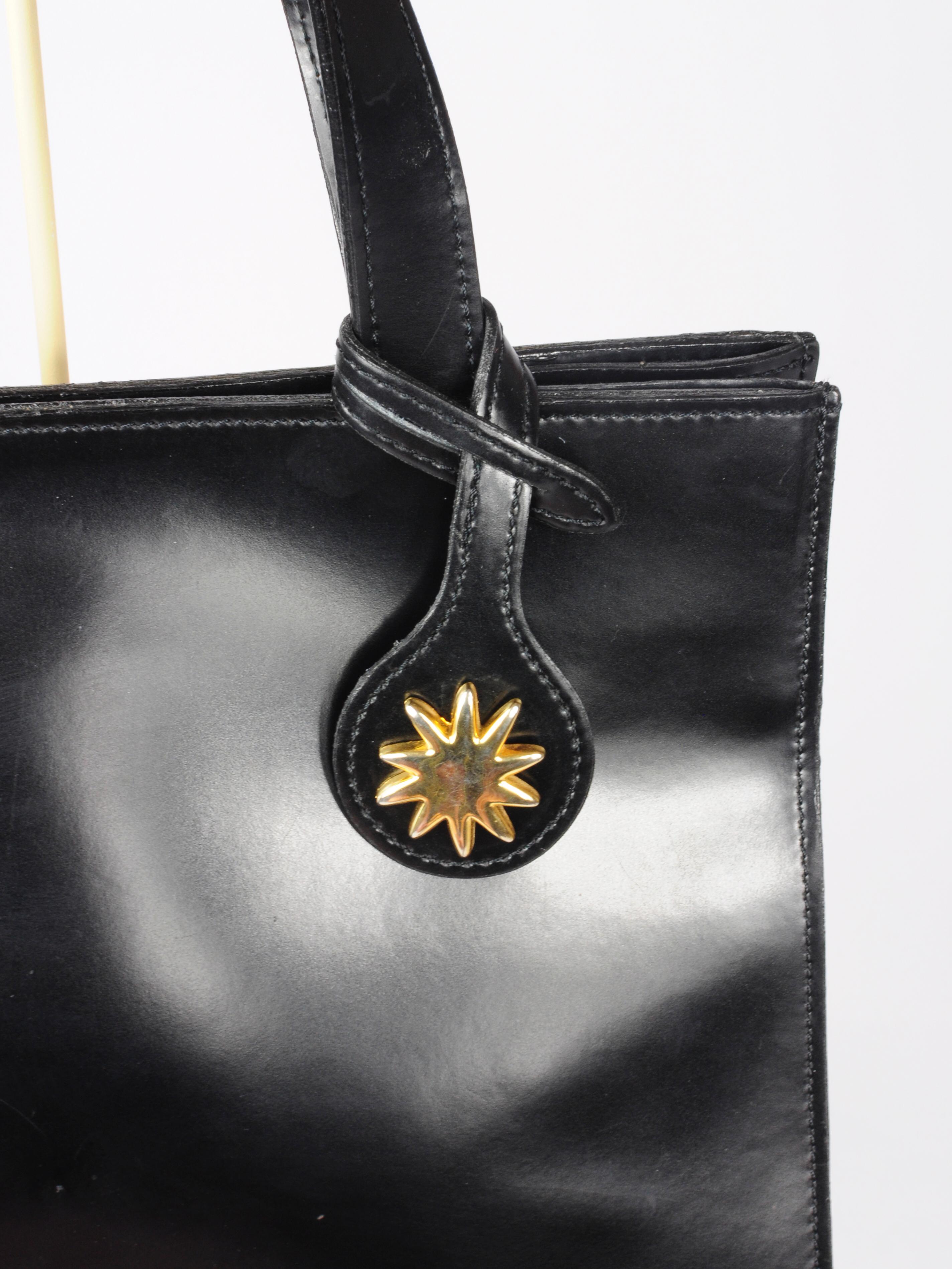 Edouard Rambaud top handle patent leather handbag with interchangeable gold and blue sun brooch pins. The bag comes with a gold sun pin and a silver sun pin, and are interchangeable depending on how you want to match with your outfit. The sun charm