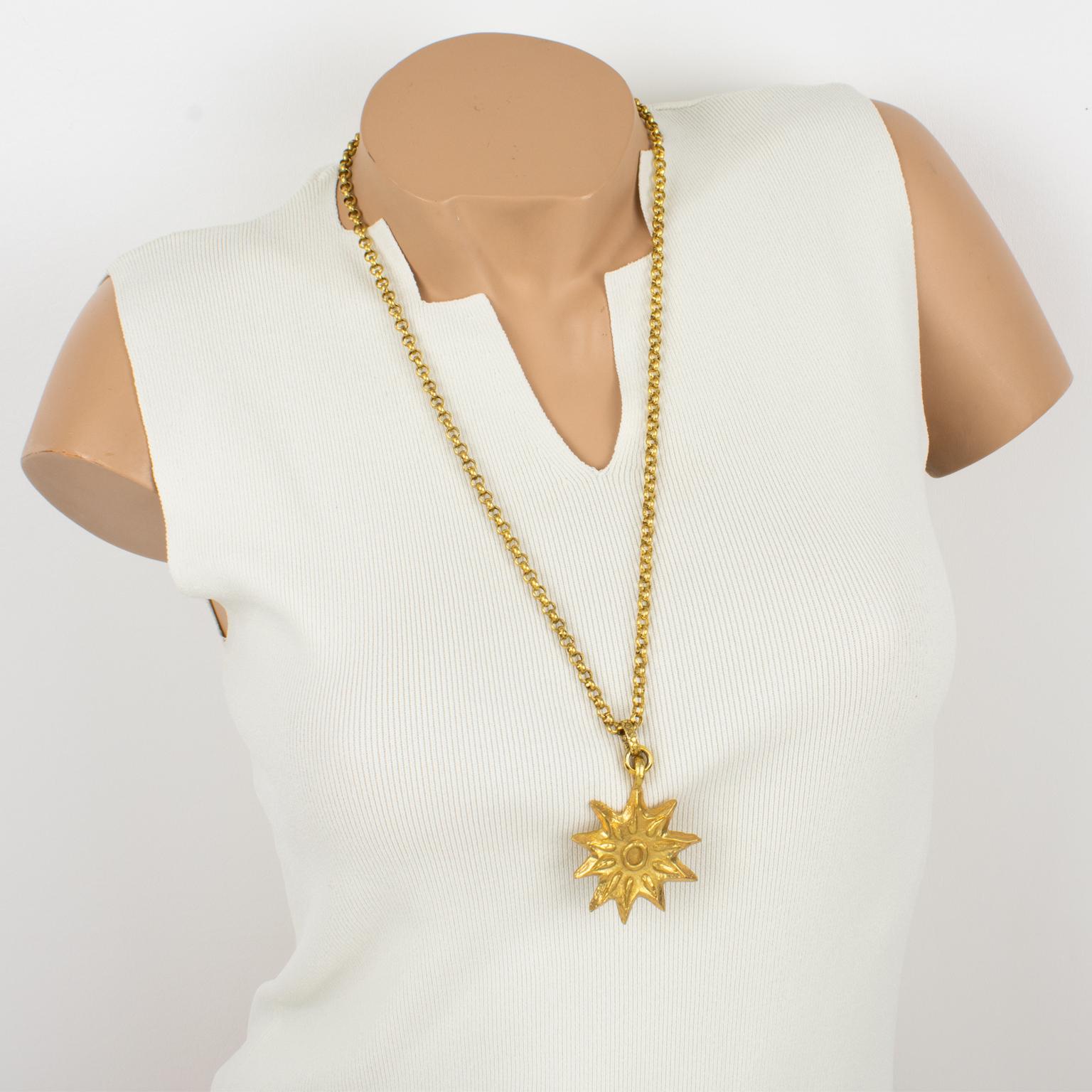 This lovely Edouard Rambaud Paris pendant necklace features a stylized dimensional sun design with gilded metal, all textured, in a semi-mat finish aspect. The long gilt metal chain has a spring-ring closing clasp. The pendant is marked on the