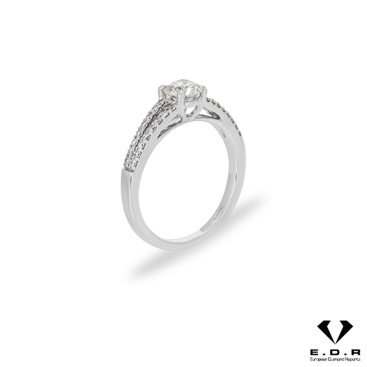 A unique 18k white gold diamond engagement ring. The ring features a round brilliant cut diamond set to the centre in a four prong mount weighing 0.51ct, H colour and VS1 clarity. The centre diamond is further complemented by a split shank pave set
