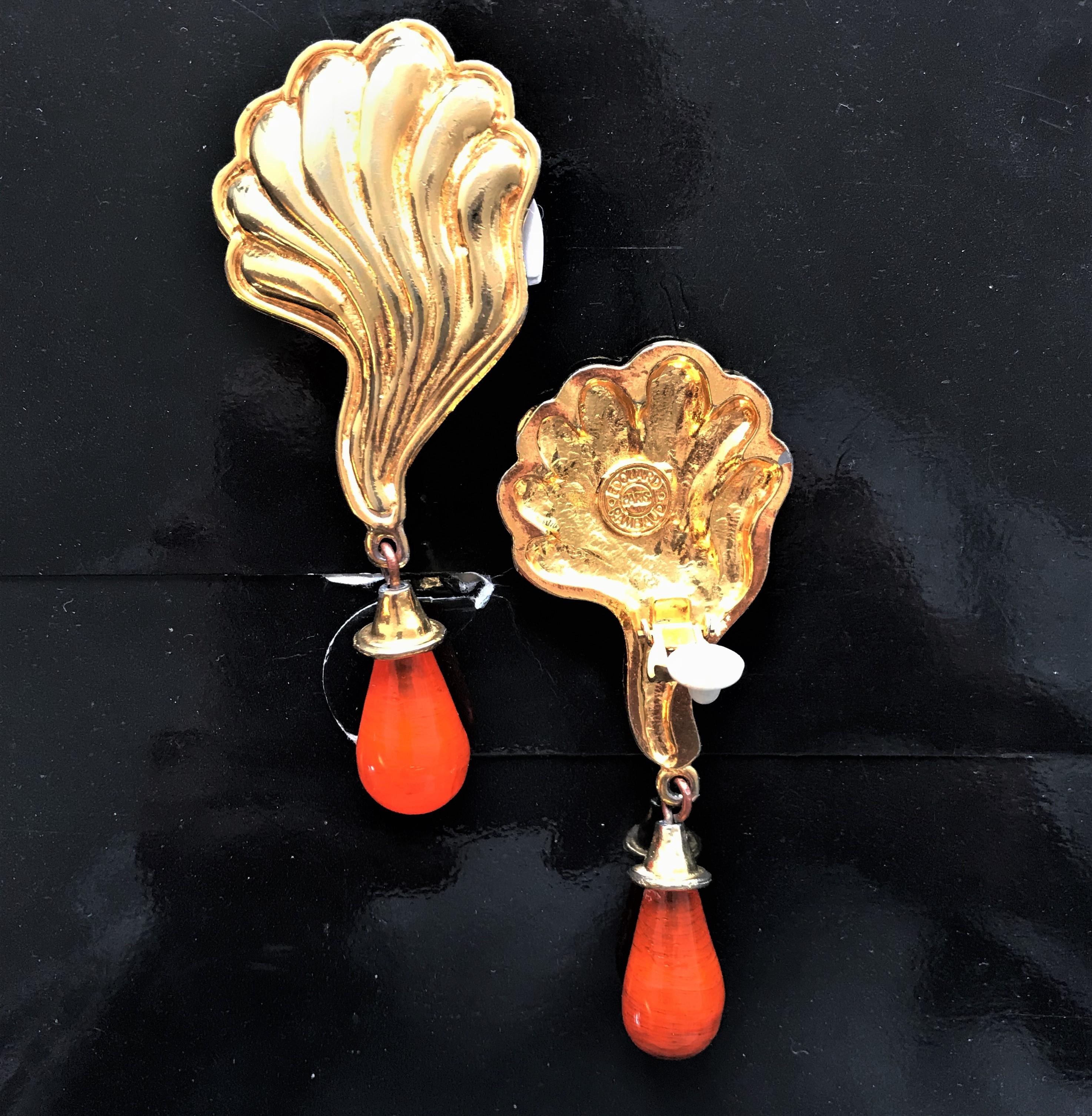 Ein sehr stilvoller Ohrclip von Eduard Ramboud Paris in Form eines muschelförmigen Blattes mit aufgesetzten orangefarbenen Glastropfen.
Maße: Gesamtlänge 10 cm, orangefarbene Tropfen 3 cm, Breite 4 cm.
Bitte beachten Sie, dass ein orangefarbener